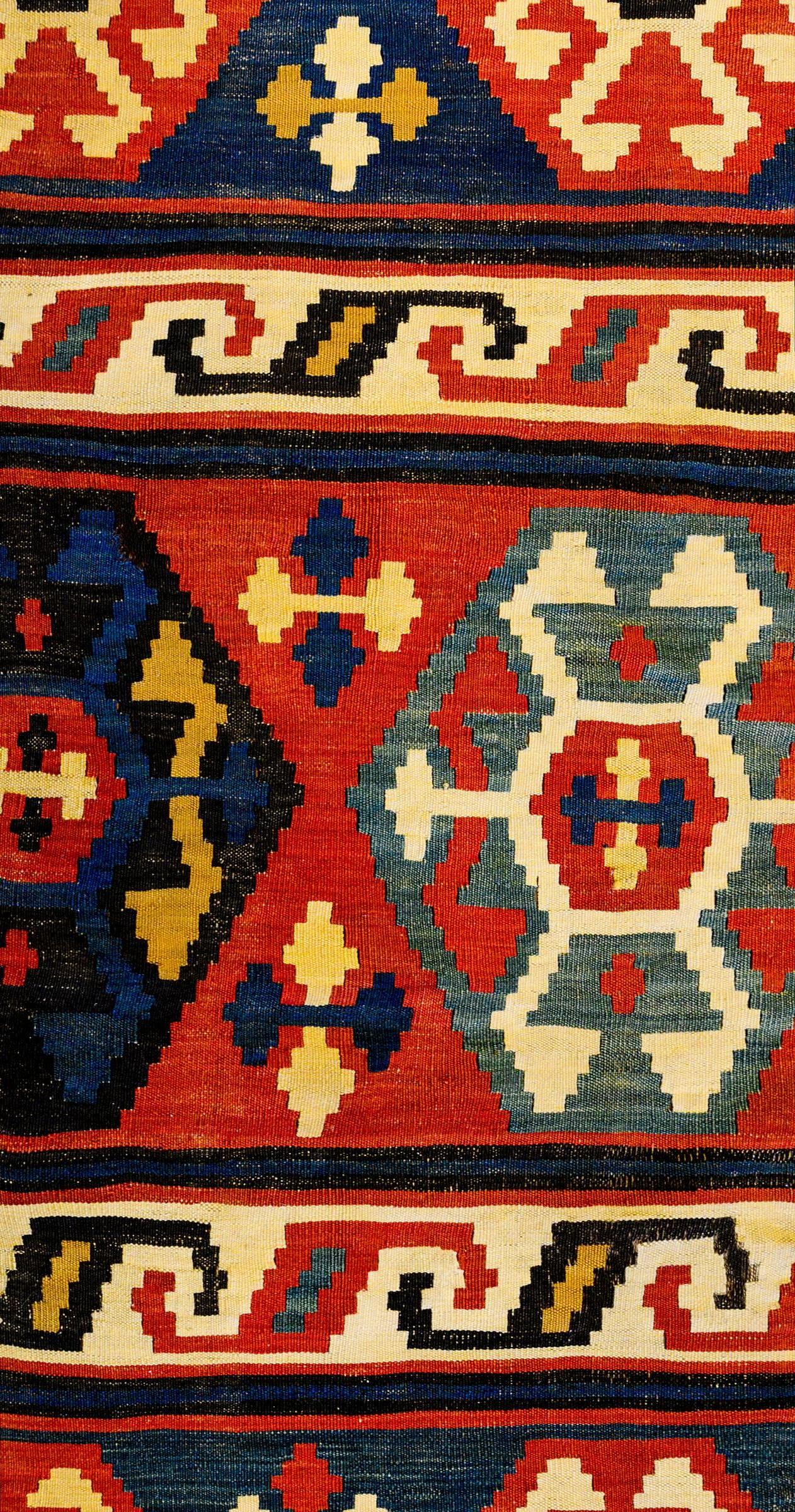 An exciting mid-20th century Caucasian Shriven Kilim rug with alternating stripes containing multicolored hexagonal shapes on crimson, indigo, and green backgrounds and S form shapes on white backgrounds.