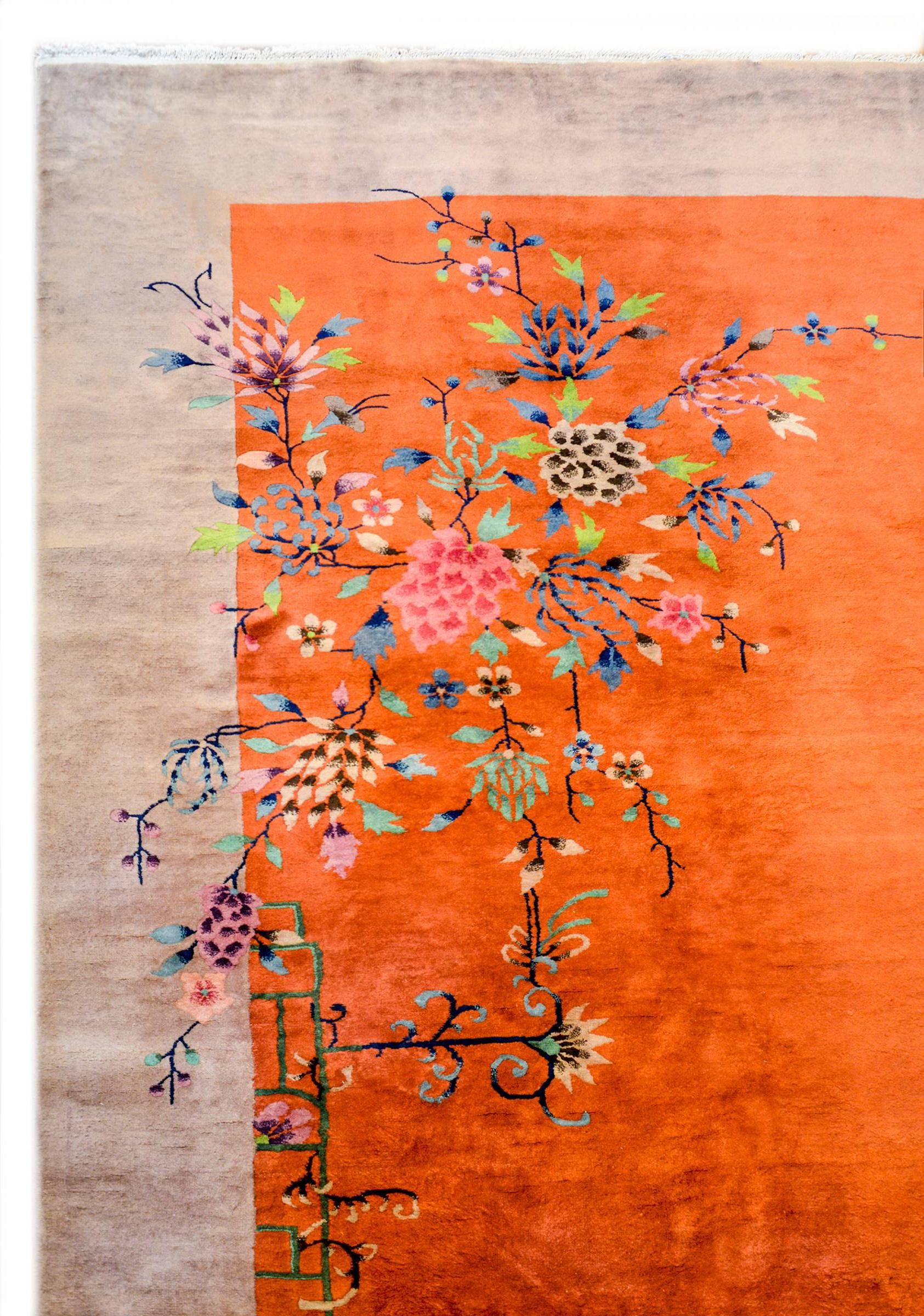An incredible early 20th century Chinese Art Deco rug with a brilliant orange field surrounded by a wide grey border. Two peony bushes with multicolored blossoms and vines live in opposite corners.