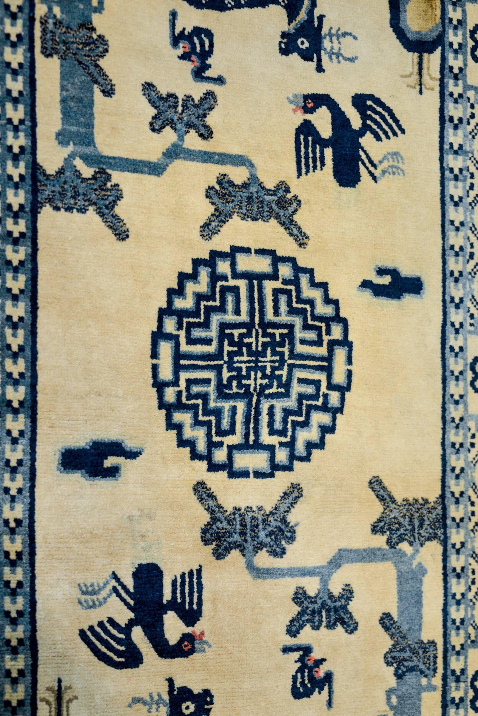 An incredible late 19th century Chinese Peking rug with a beautiful pictorial pattern with deer, phoenix, bats, and a tree flanking a central medallion all woven in light and dark indigo on a cream colored background. The border is wide containing