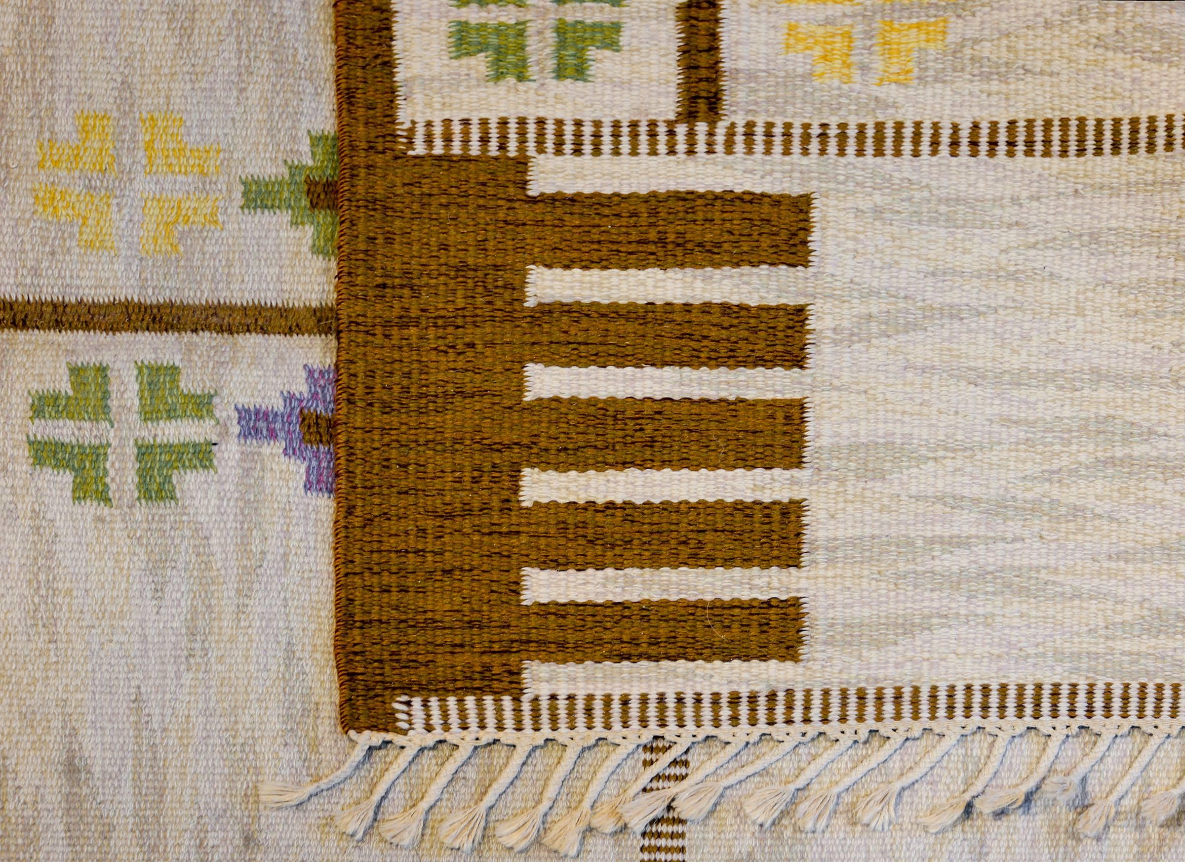 A wonderful vintage Swedish flat-weave Kilim with a sweet floral pattern composed with multiple alternating brown geometric shapes and pink, violet, yellow, and indigo stylized flowers across the field. There is no border.