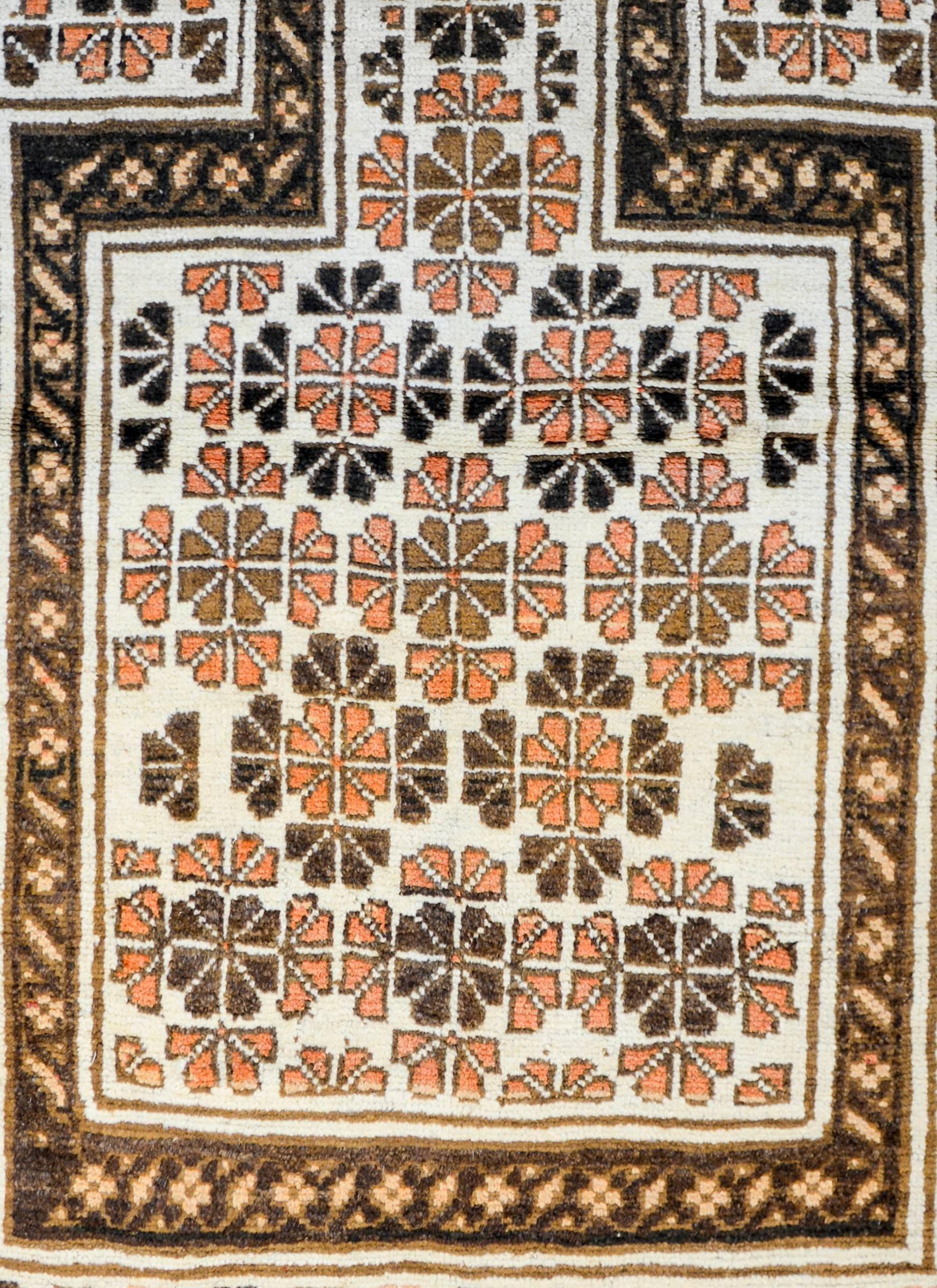 An early 20th century Persian Baluch prayer rug with an all-over floral pattern woven with light, dark, and copper colored brown wool on a cream colored background surrounded by a complementary stylized floral border women in similar colors.
  