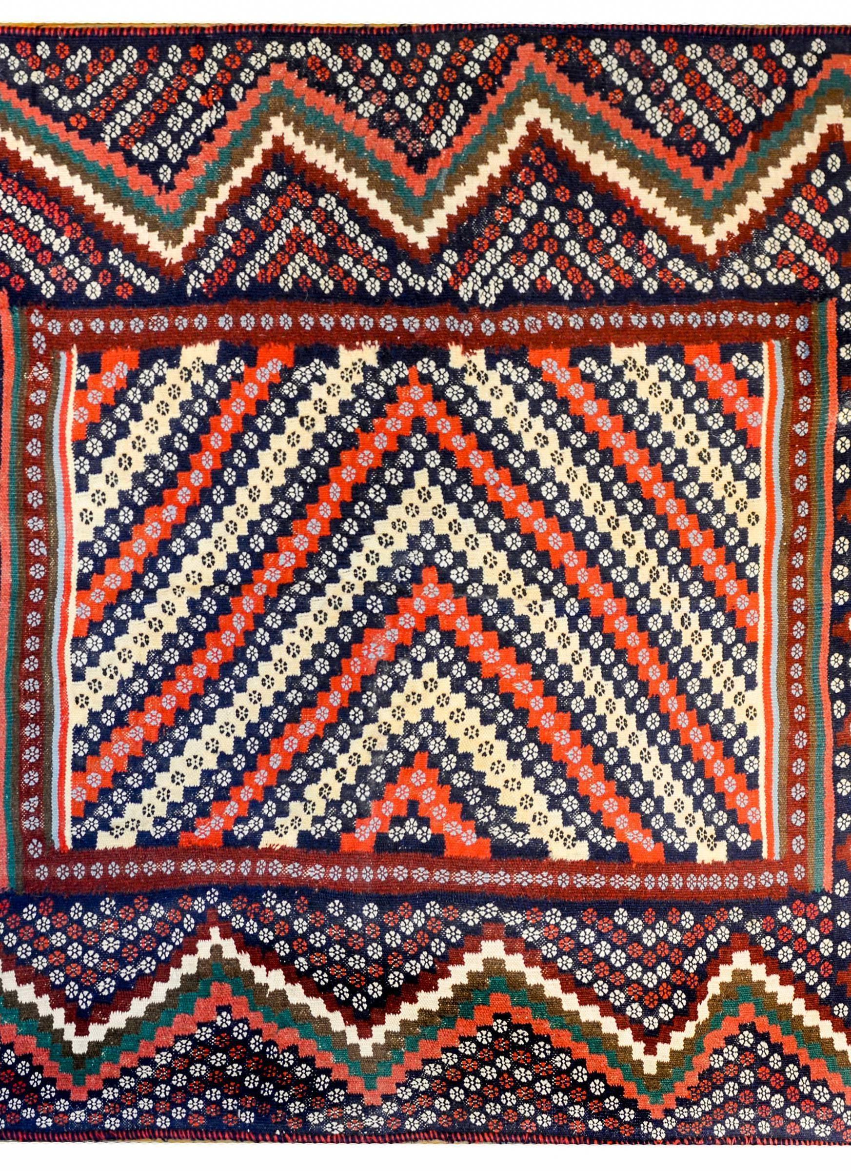 An late 20th century Turkmen Kilim rug with a beautiful elaborate pattern of alternating colored stripes of crimson, indigo, and cream, each with a petite floral design, surrounded by a multiple elaborate zigzag borders.