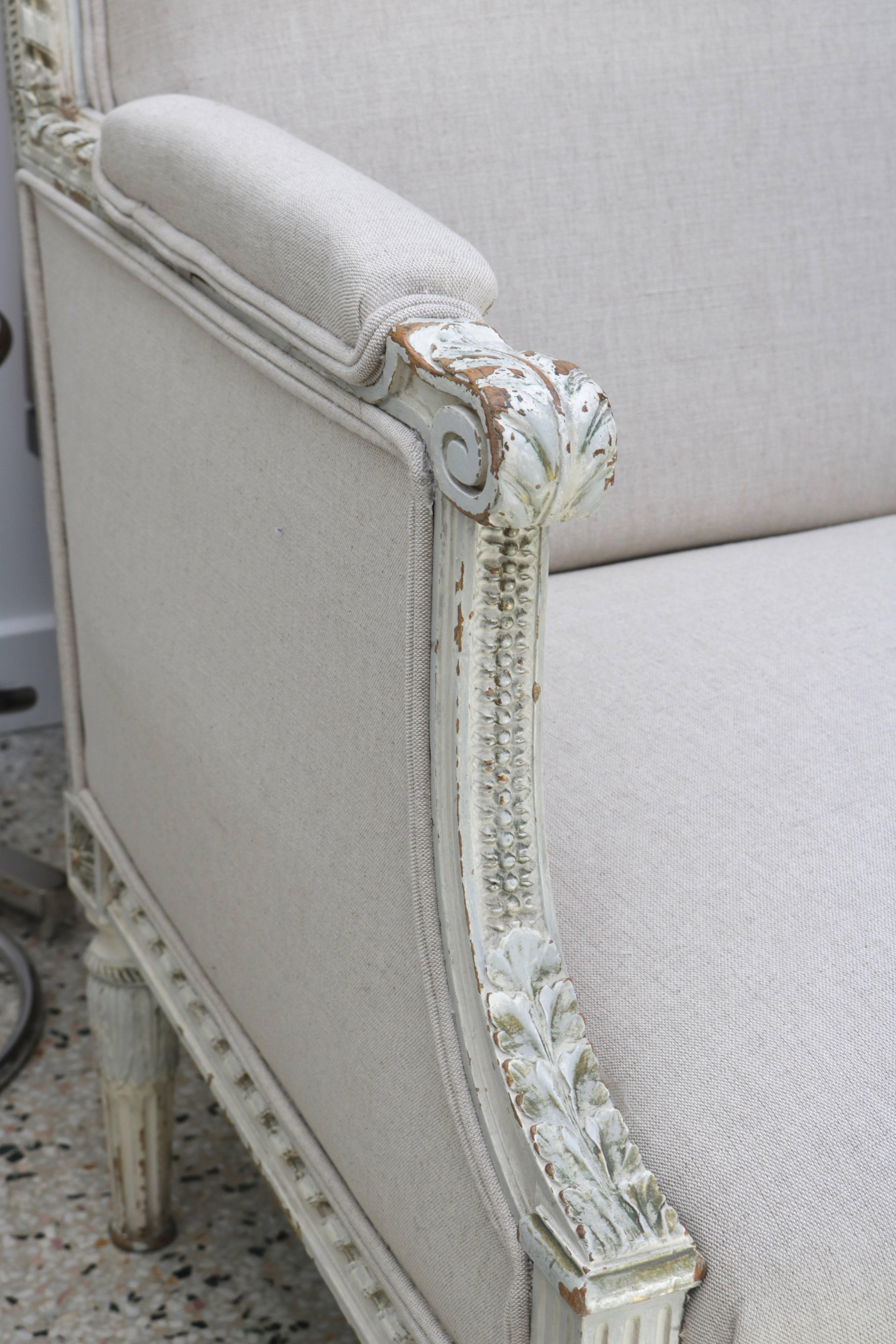 This stylish Louis XVI style settee was recently purchased in London and has been professionally reupholstered in a linen-like, woven beige/tan coloration fabric which works beautifully with the off-white and bronze/green painted frame.

Note:  The