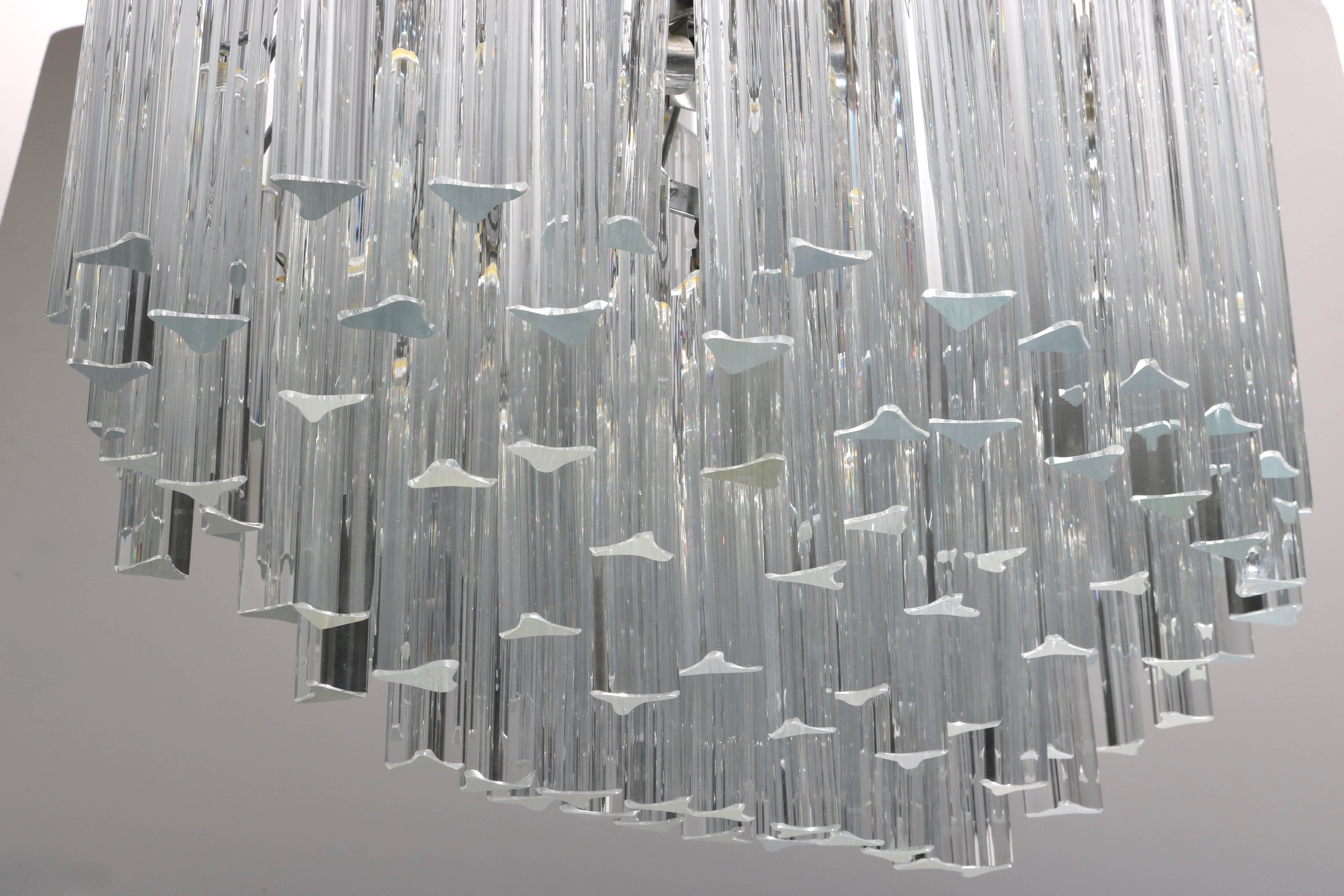 This stylish Mid-Century Modern chandelier with its oval shape will make the perfect addition above your dinging table or perhaps in a hallway. The clear Venini Murano prisms sparkle with the light playing thru its tiered layers.