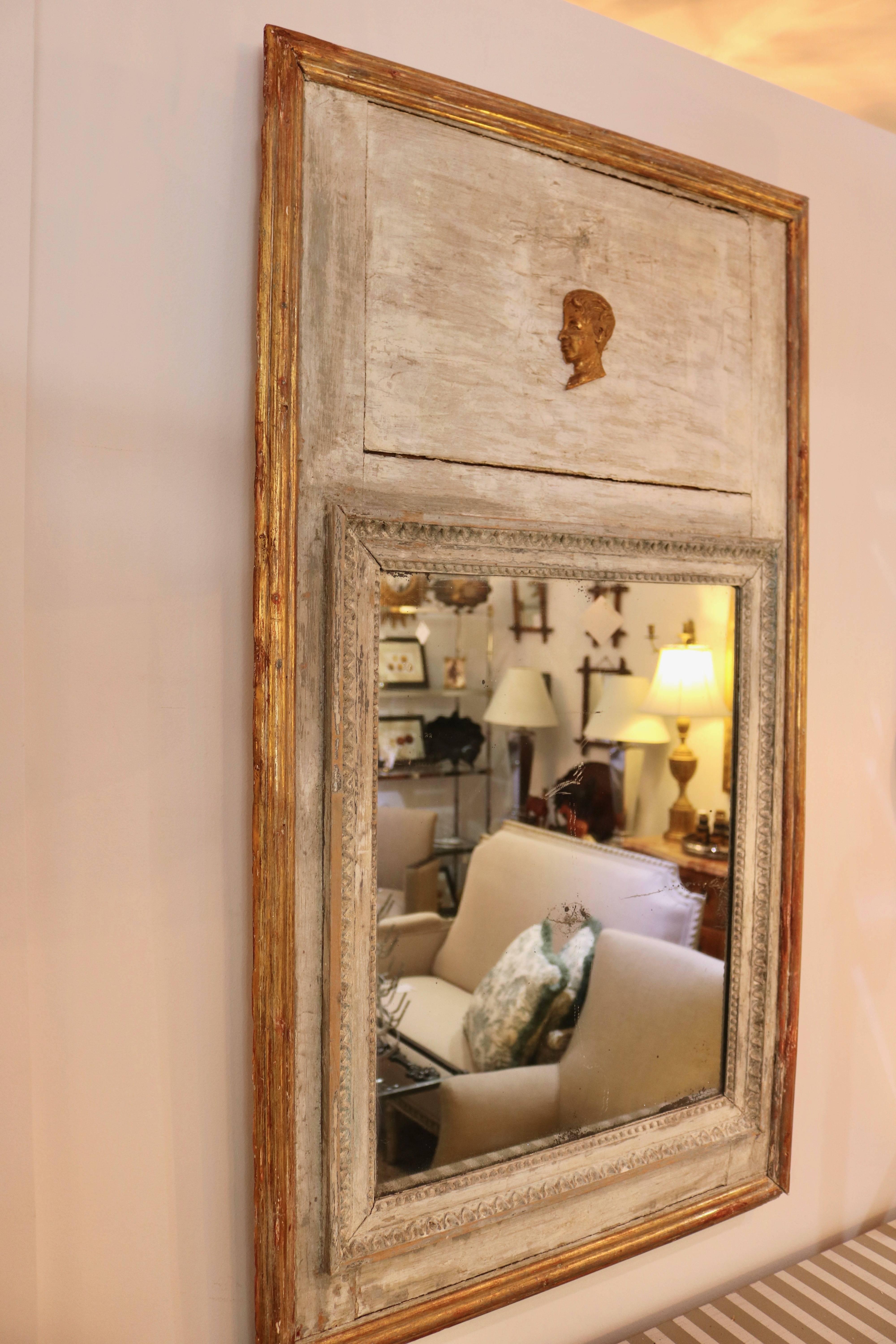 This charming trumeau mirror dates from the 1820s and was recently purchased in London. The pieces retains its original mirror which does show oxidation of the silver backing (see image #8). The soft gray paint compliments the gilt gold moulding and