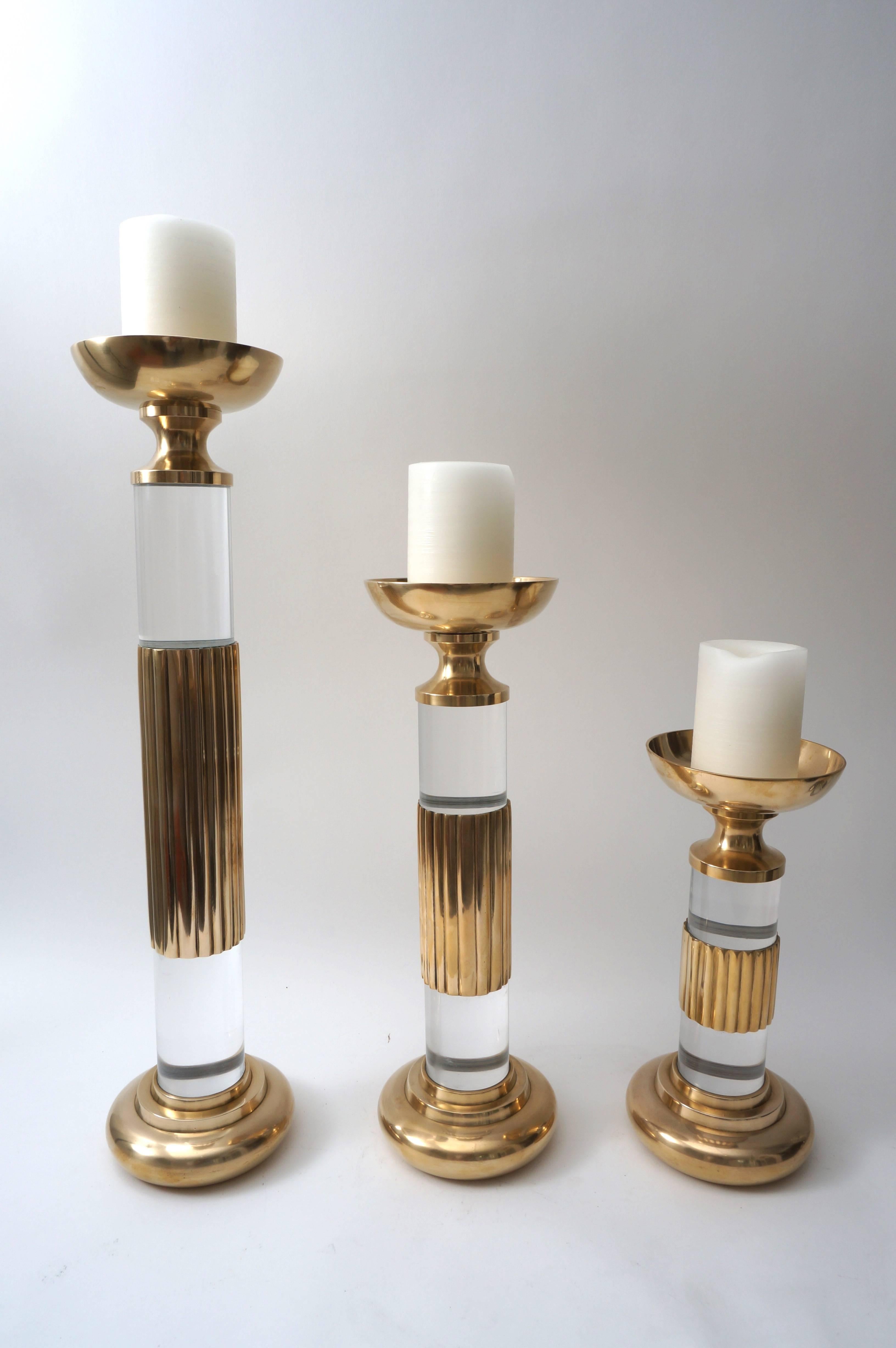 This stylish set of candlesticks date to 1987 and were fabricated by Dolbi Cashier in polished brass and Lucite. 

Note: Dimensions of tallest piece 23.63