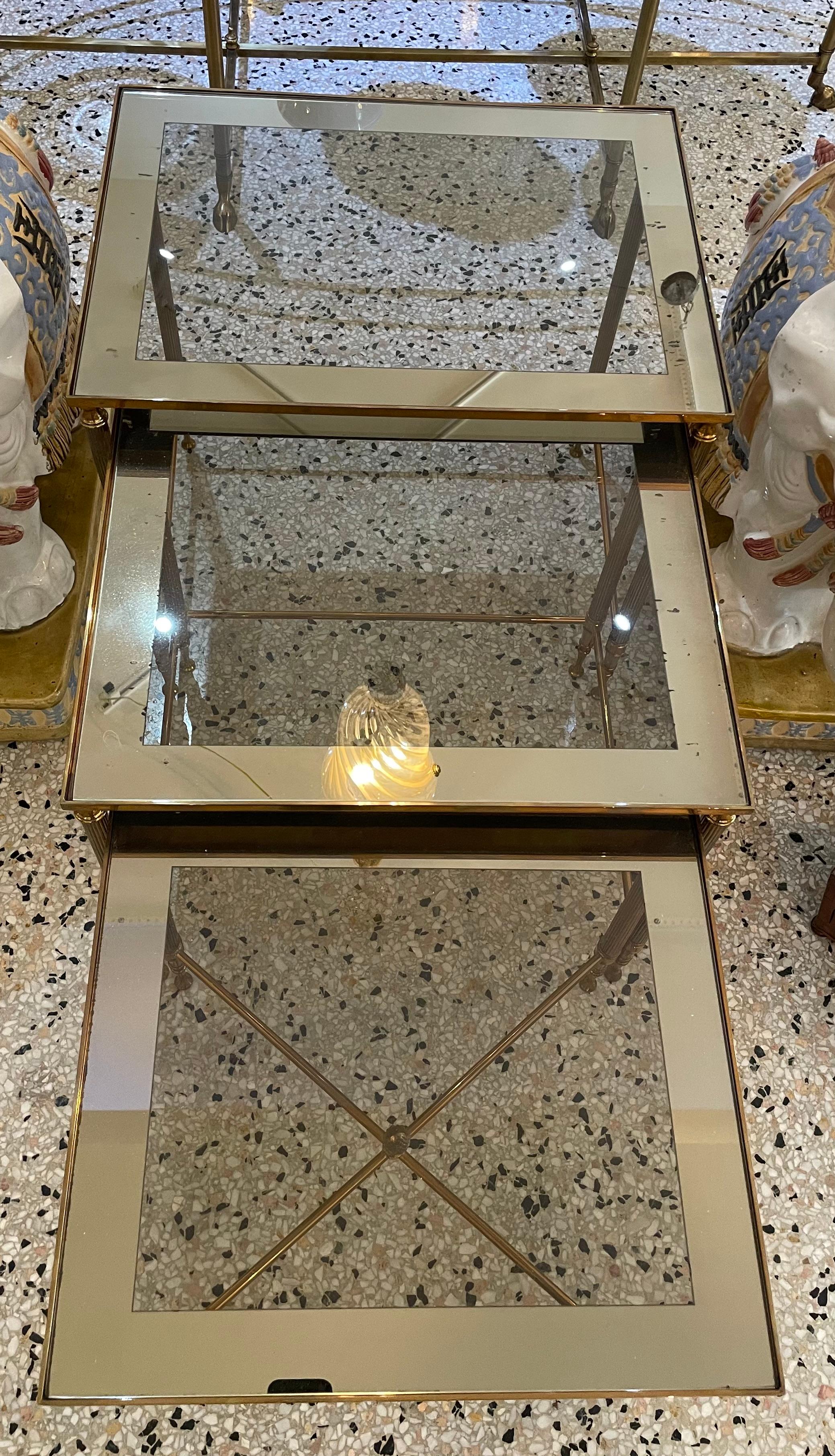 This stylish three piece set of brass nesting tables date to the 1970s and are attributed to Maison Jansen

Note: The inset tops are clear glass with a mirror border.

Note: Largest table dimensions are 19.13