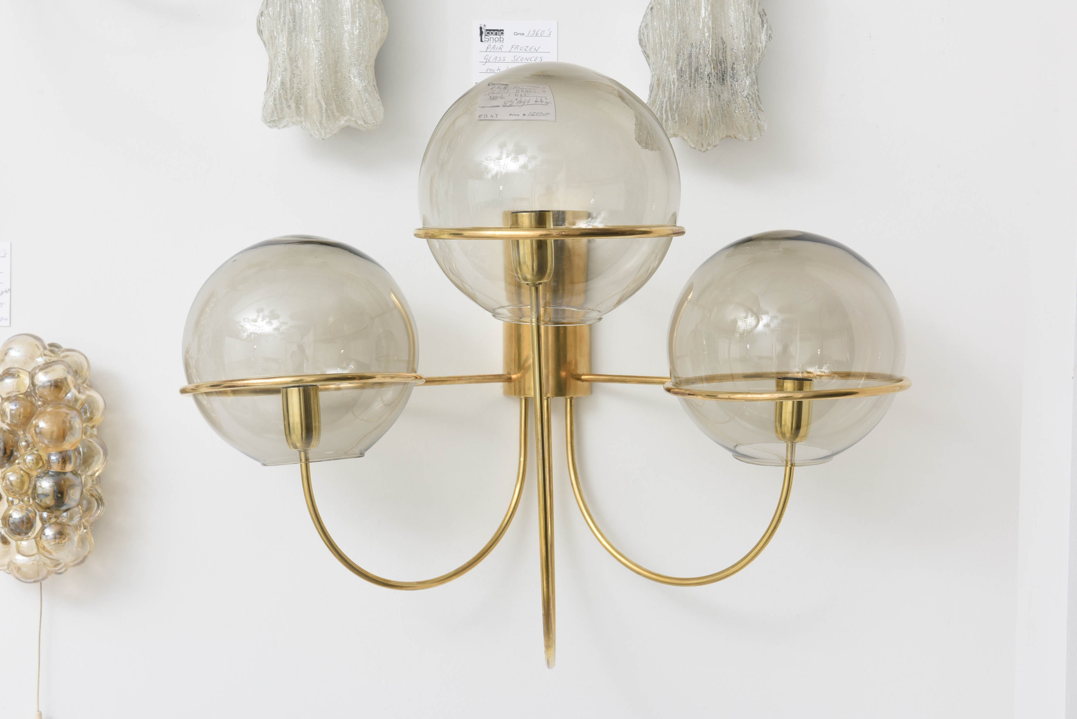These amazing large-scaled Mid-Century Modern wall sconces in polished brass with smoked-glass globes were produced by Koeln Leuchten of Germany in the 1960s. 

These pieces are large in their size yet quite delicate and elegant in their