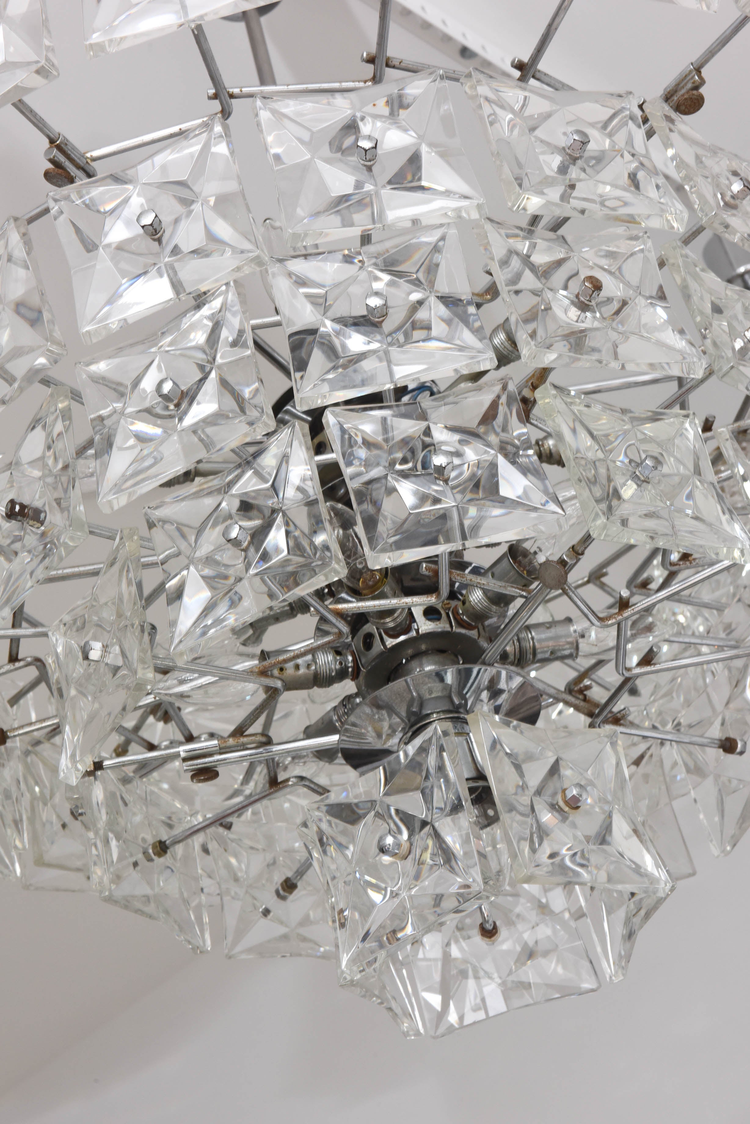 This Mid-Century Modern chandelier with its five-tiers of square-shaped crystals with faceted-stars was produced in the 1970s by the iconic firm Kinkeldey lighting based in Bad Pyrmont, Germany. 

The main body of the piece is 15" height x