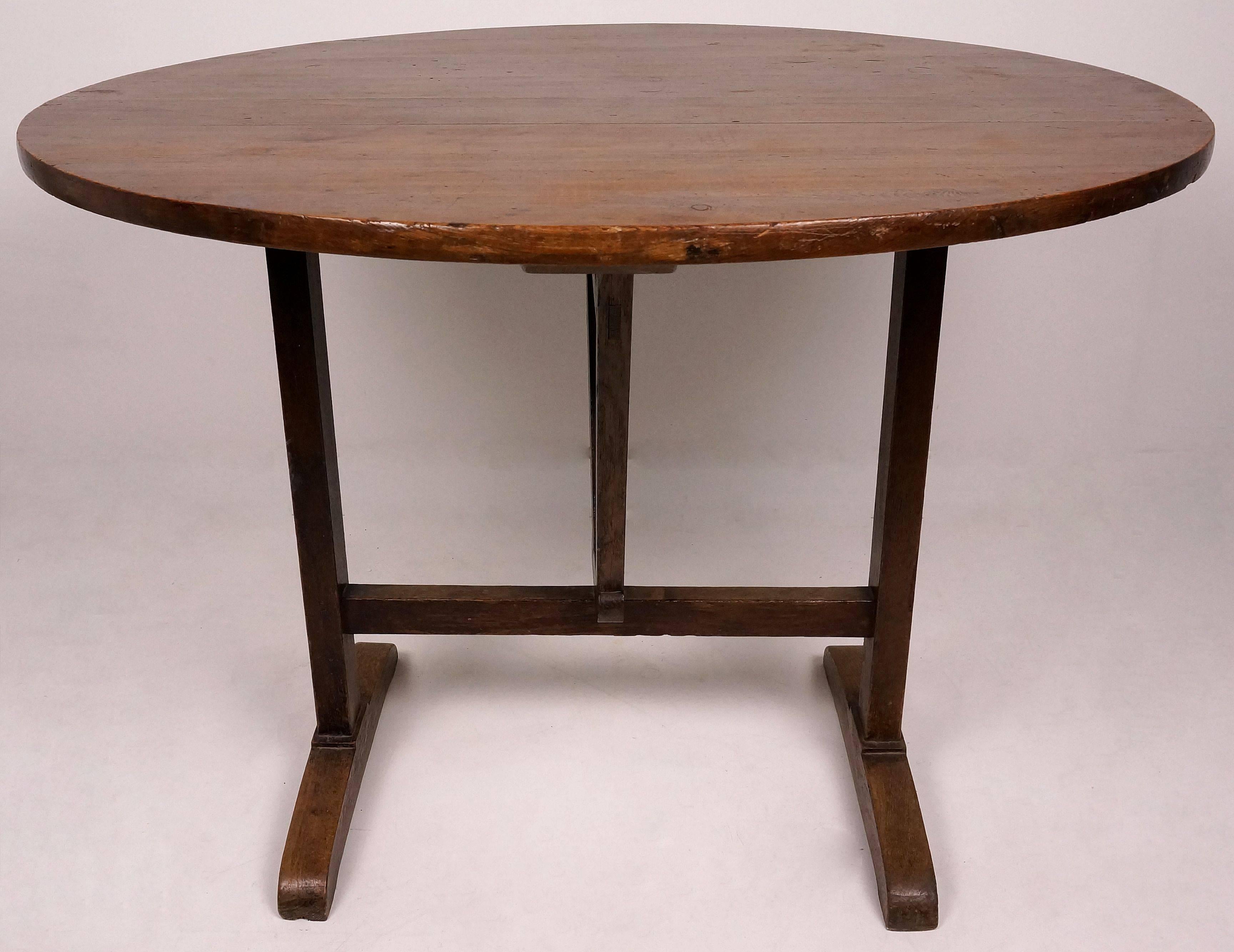 This French Provencal vendage wine tasting table with its trestle-base and wide-plank oval-top is from the late 19th century and is fabricated of oak and pine which has mellowed to a beautiful dark lustrous coloration.  

The oval-top easily