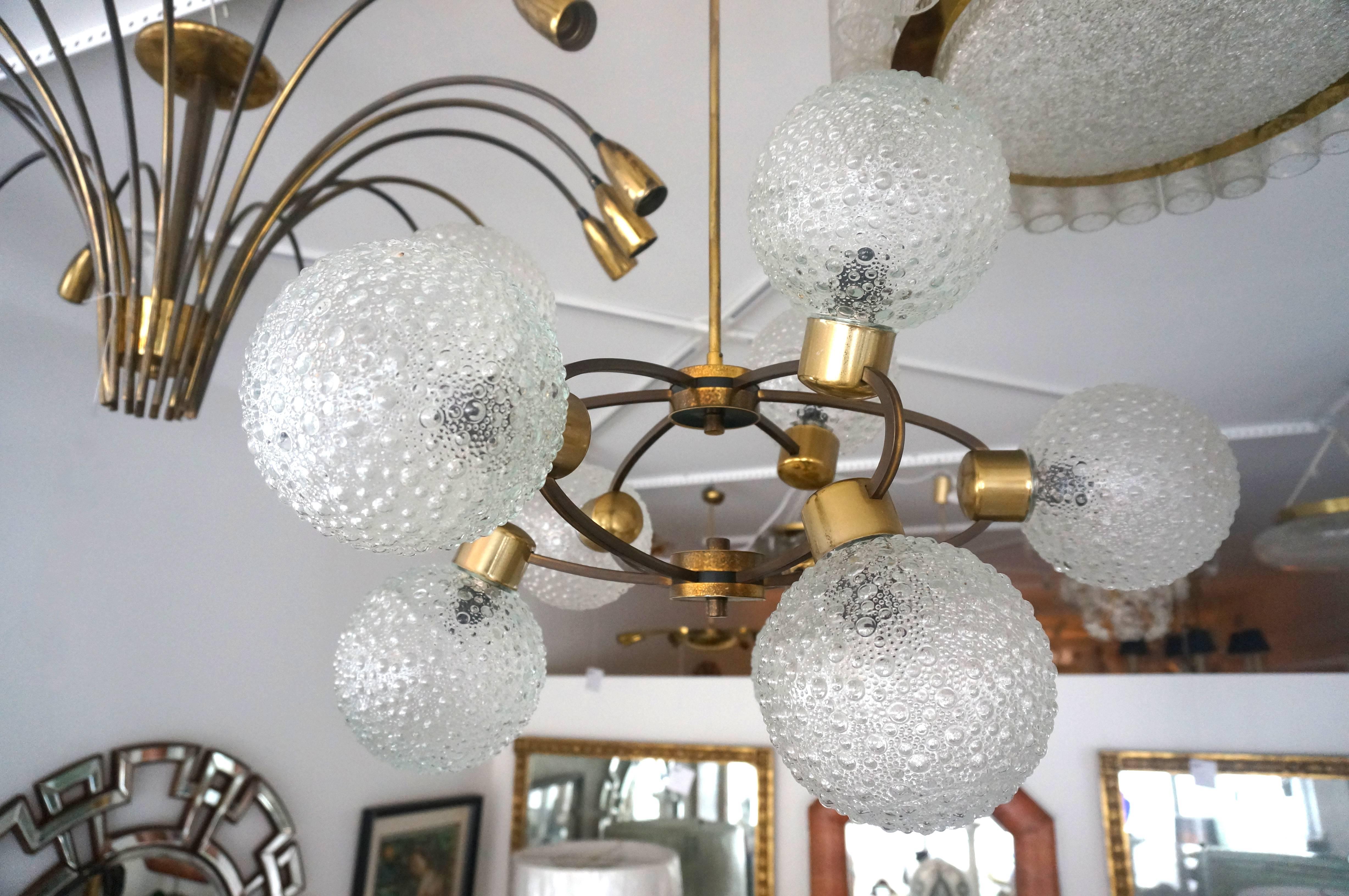 This 1960s chandelier captures the spirit of the atomic-age with its stylized molecular presence. The textured-glass globes seem to be the atoms of energy or perhaps the orbit of the planets.

Note: Dimensions of the glass globes is 6".

Note: