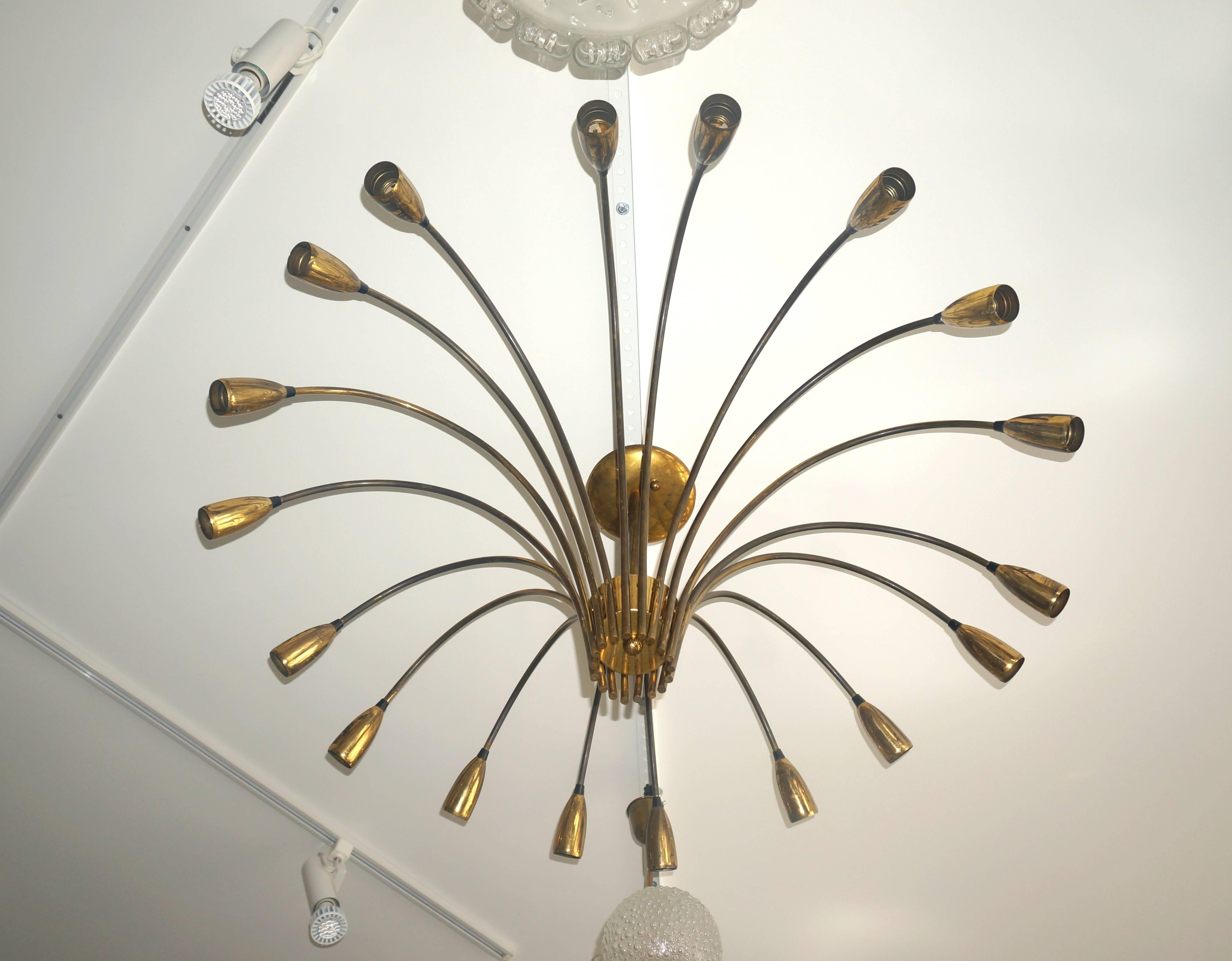 This large-scale flush mount chandelier is very much in the style of pieces created by the iconic lighting company Stilnovo in Italy.

The piece was originally a bright brass coloration which has darkened over the many years since its creation in