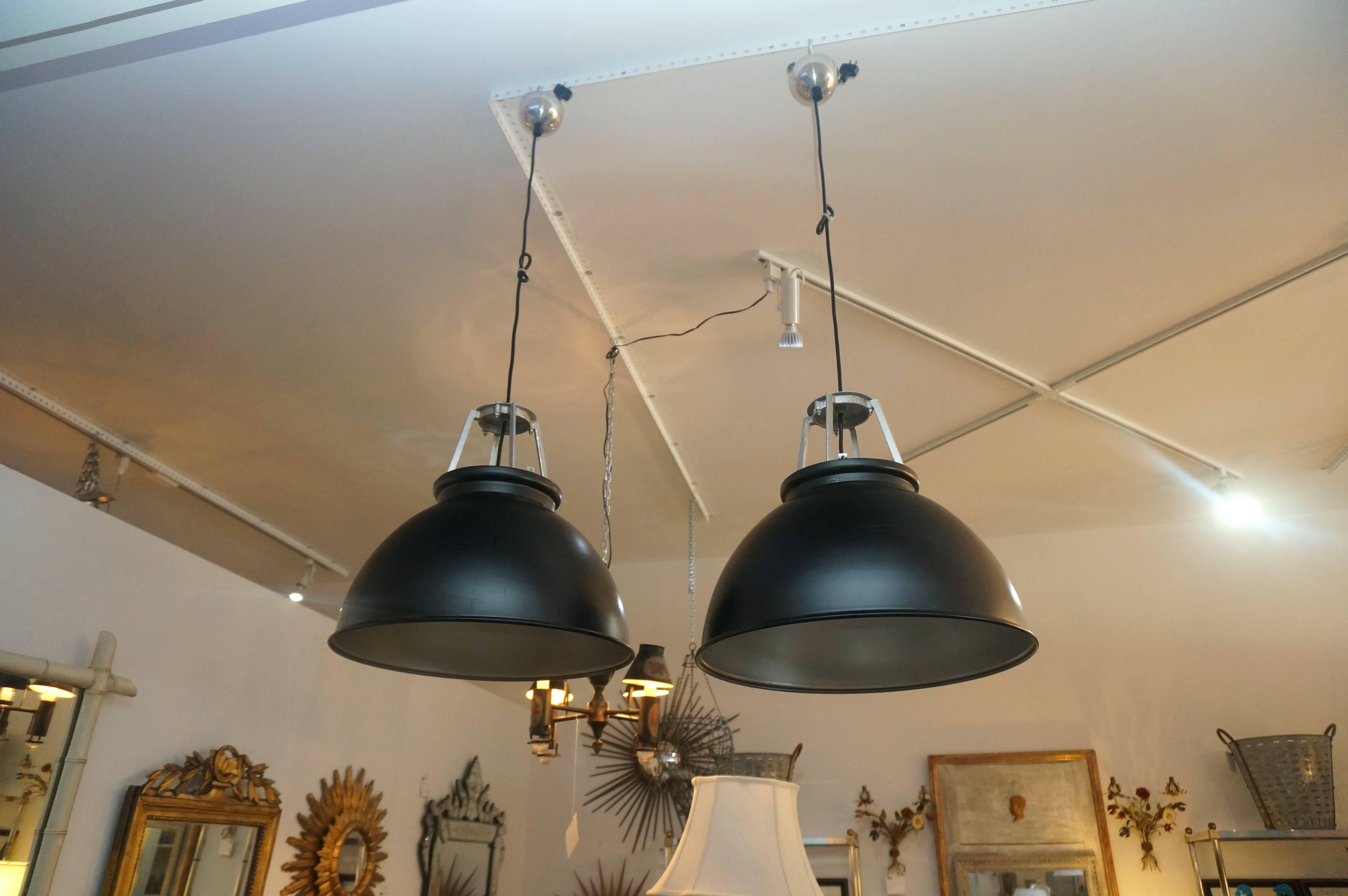 This pair of 1940s industrial style light fixtures were purchased in London (originated in France) and have been professionally restored with new wiring and paint. The exterior is a dark black with soft-silver/aluminum painted accents.

Note: The