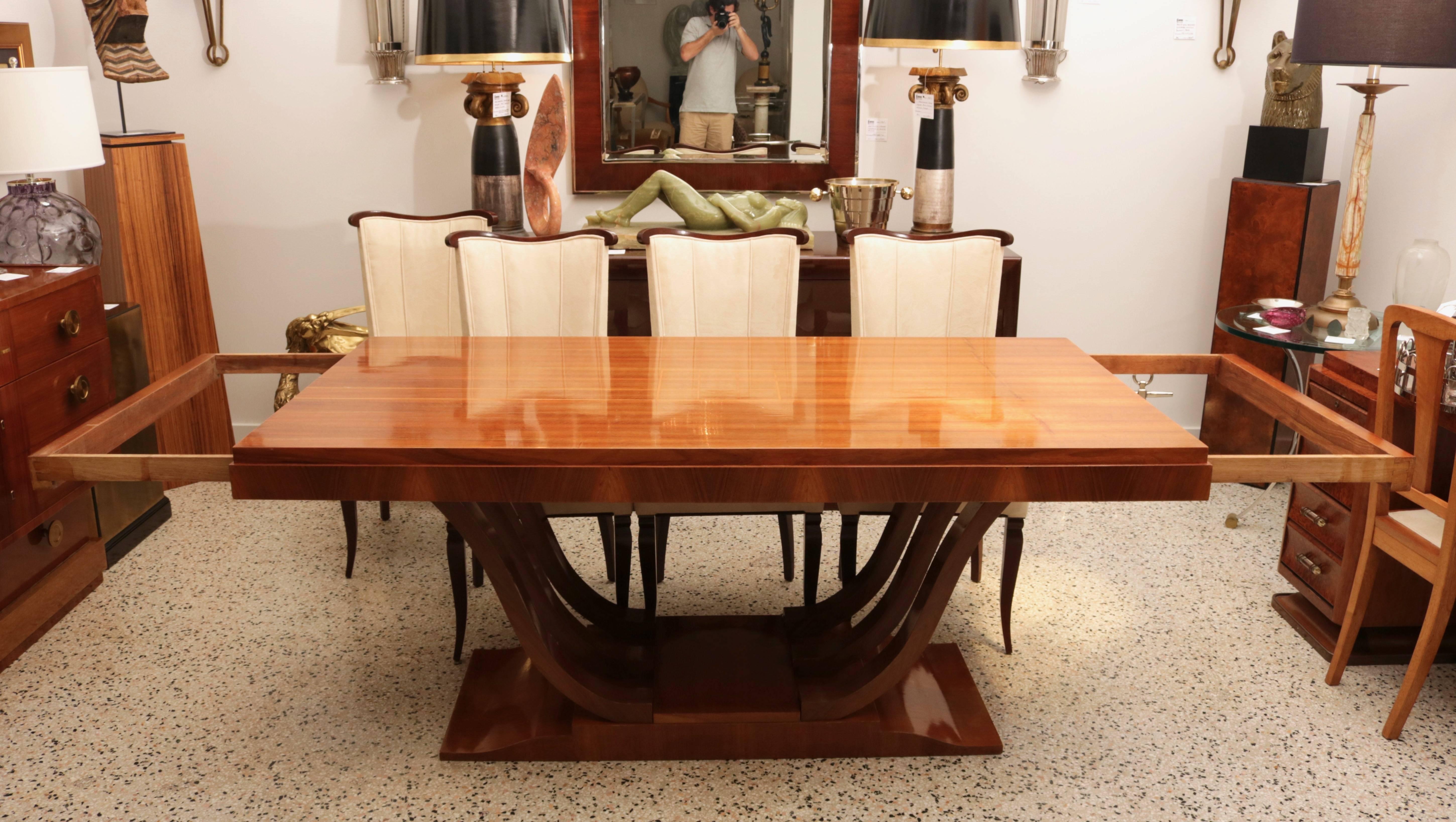 This art deco dining table is the perfect size for a narrow dining room and yet with its leaves installed the table can easily seat eight to ten people. The wood has a soft, golden coloration in a soft mahogany with an inset grid pattern medallion