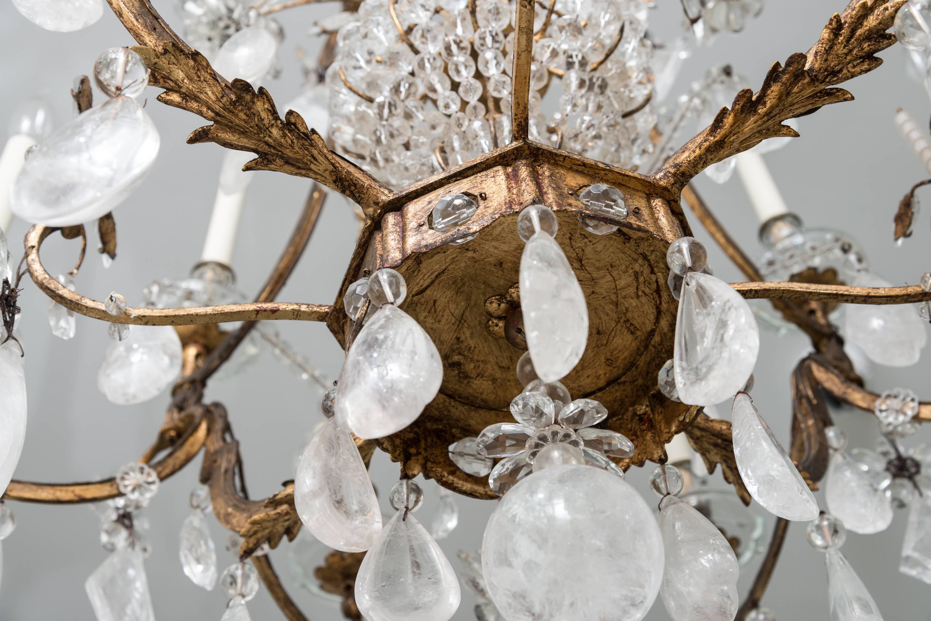 This large-scale, twelve-light Louis XVI style chandelier was created by the iconic firm of Maison Baguès of France. The piece dates to the 1930s and is fabricated of leaf gilt gold iron and a combination of rock crystal and clear crystal prisms