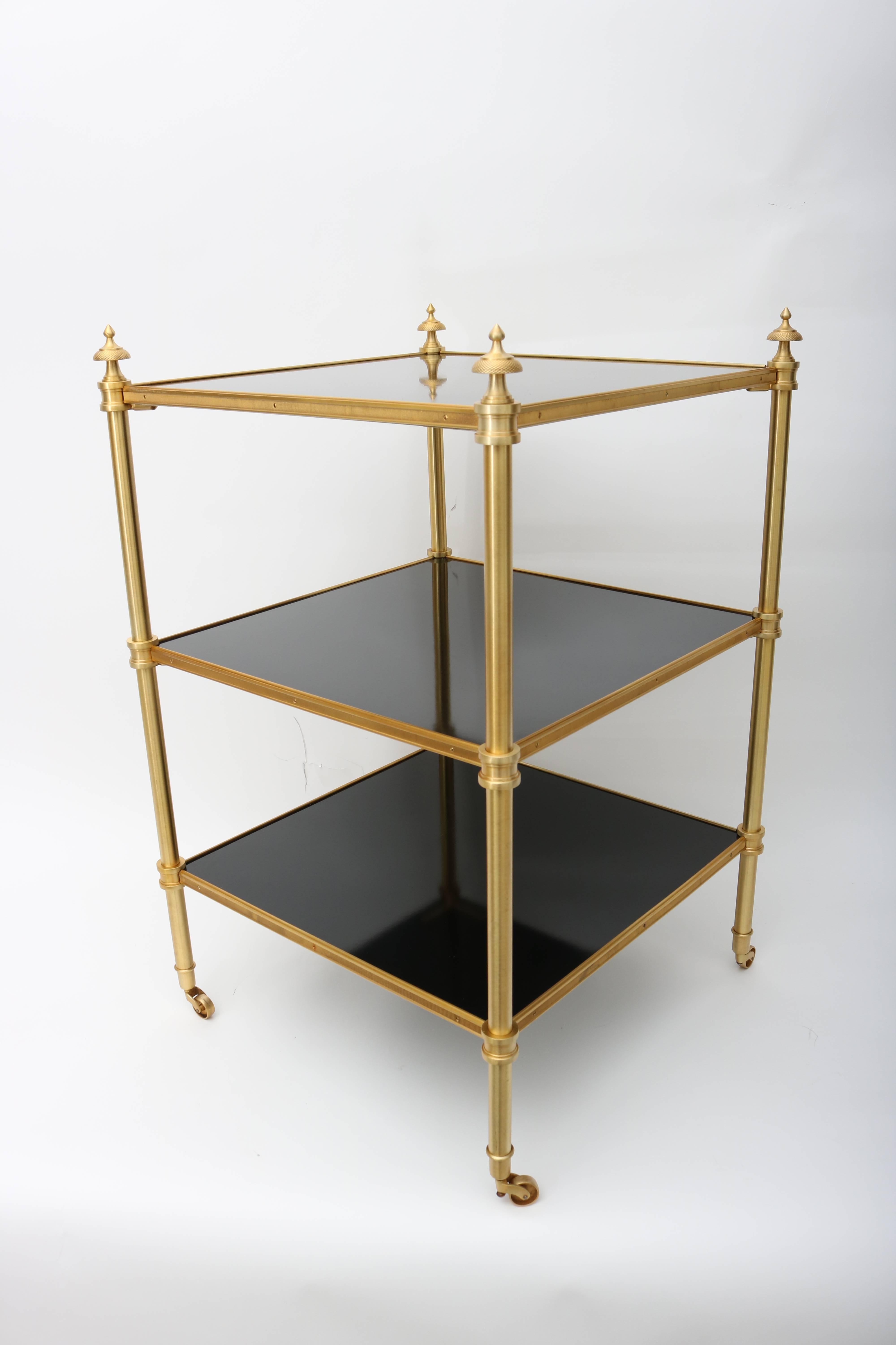 This stylish pair of Maison Jansen side tables were designed by Stephane Boudin and date to the 1950s-1960s.  They are cast brass with a gold wash finish and inset (recently restored) black lacquered panels.  The caster glide with