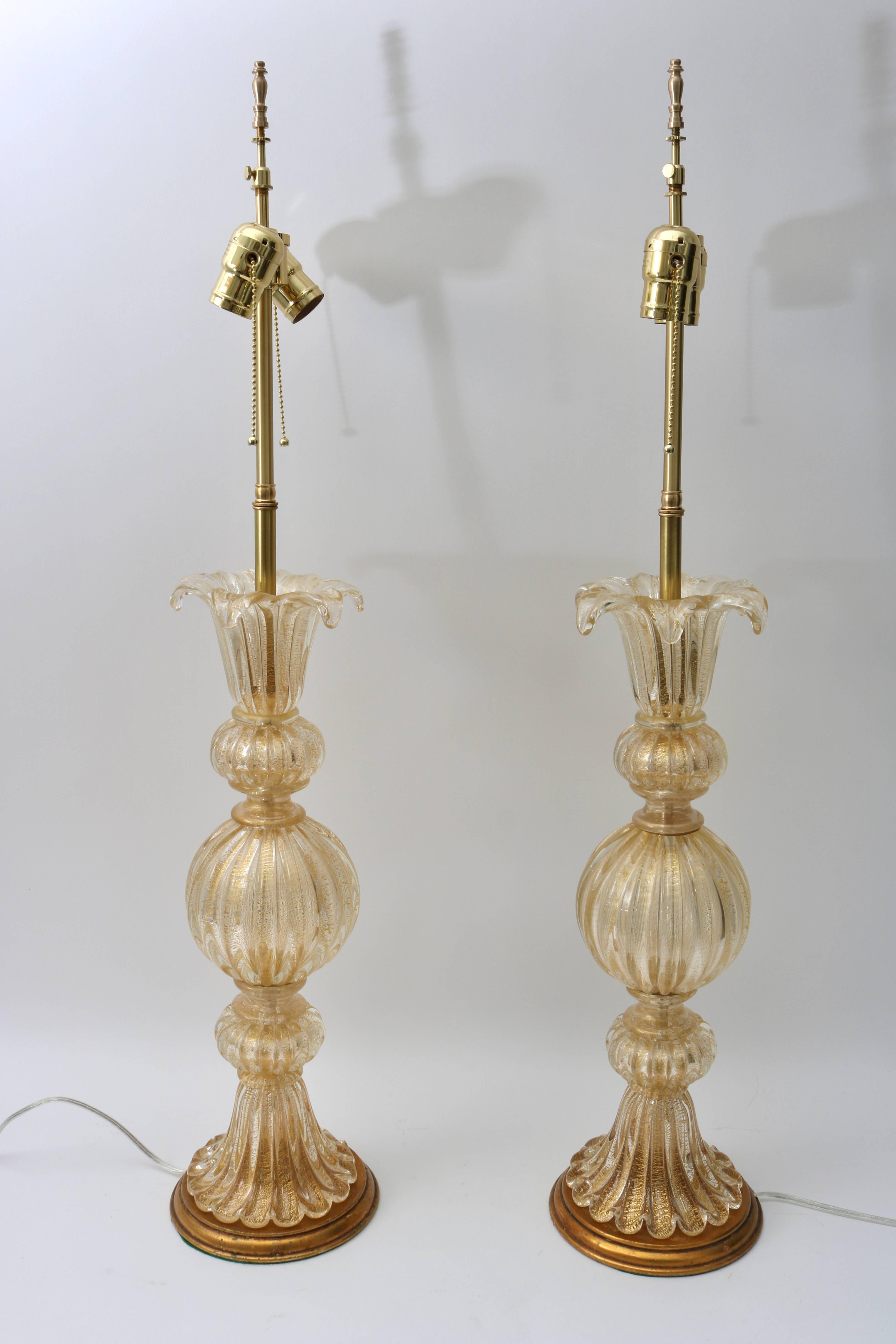 This stylish pair of Murano glass table lamps were recently acquired from a Palm Beach estate and were created in the 1960s by the iconic workshop of Barovier et Toso. They are in a clear-gold colorations with antique gold finished base and polished