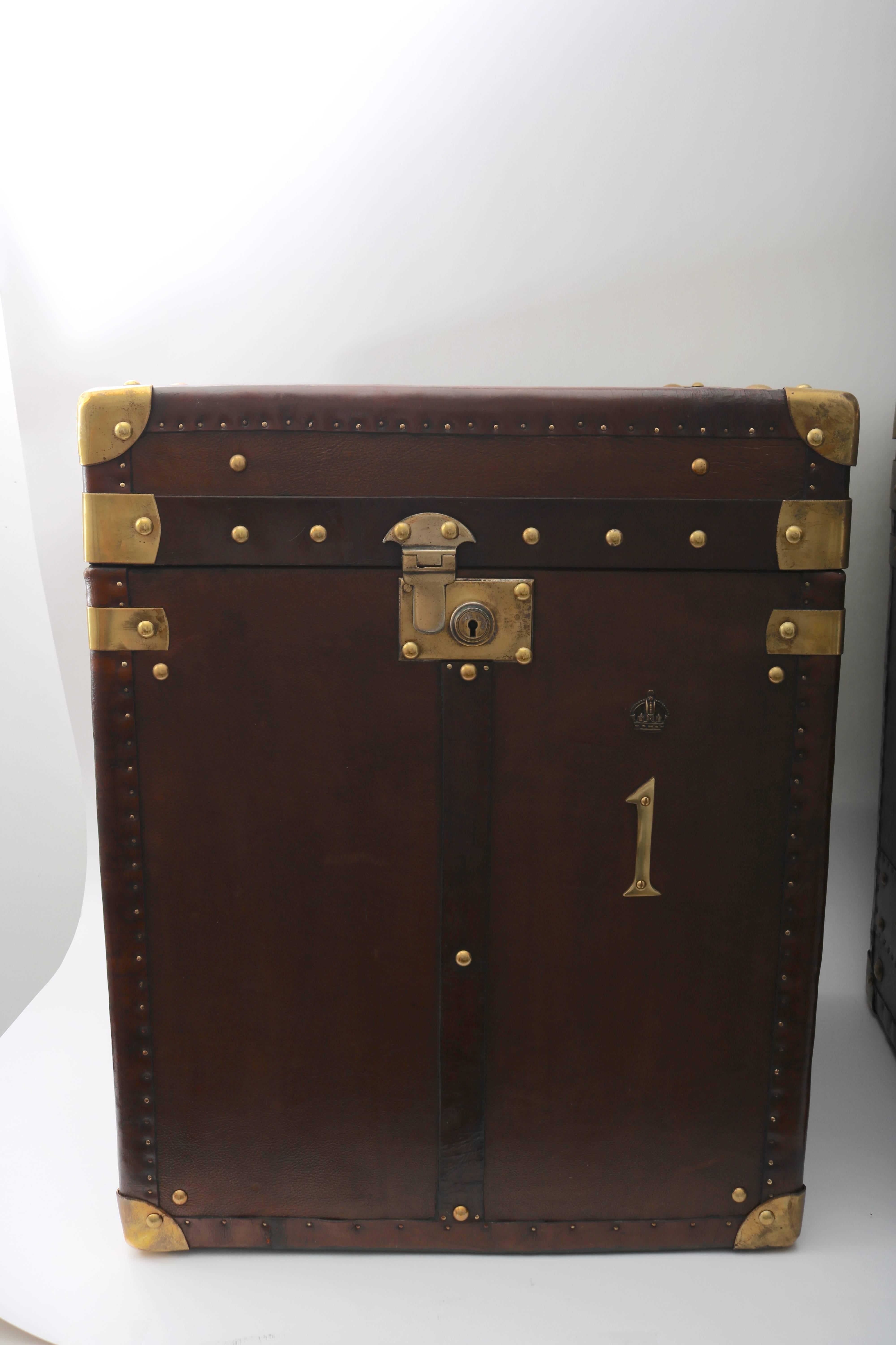 This handsome pair of leather-bound storage trunks were recently purchased in London and have been professionally restored. The leather is a dark brown and the hardware a warm-colored brass. 

 For best net trade price or additional questions