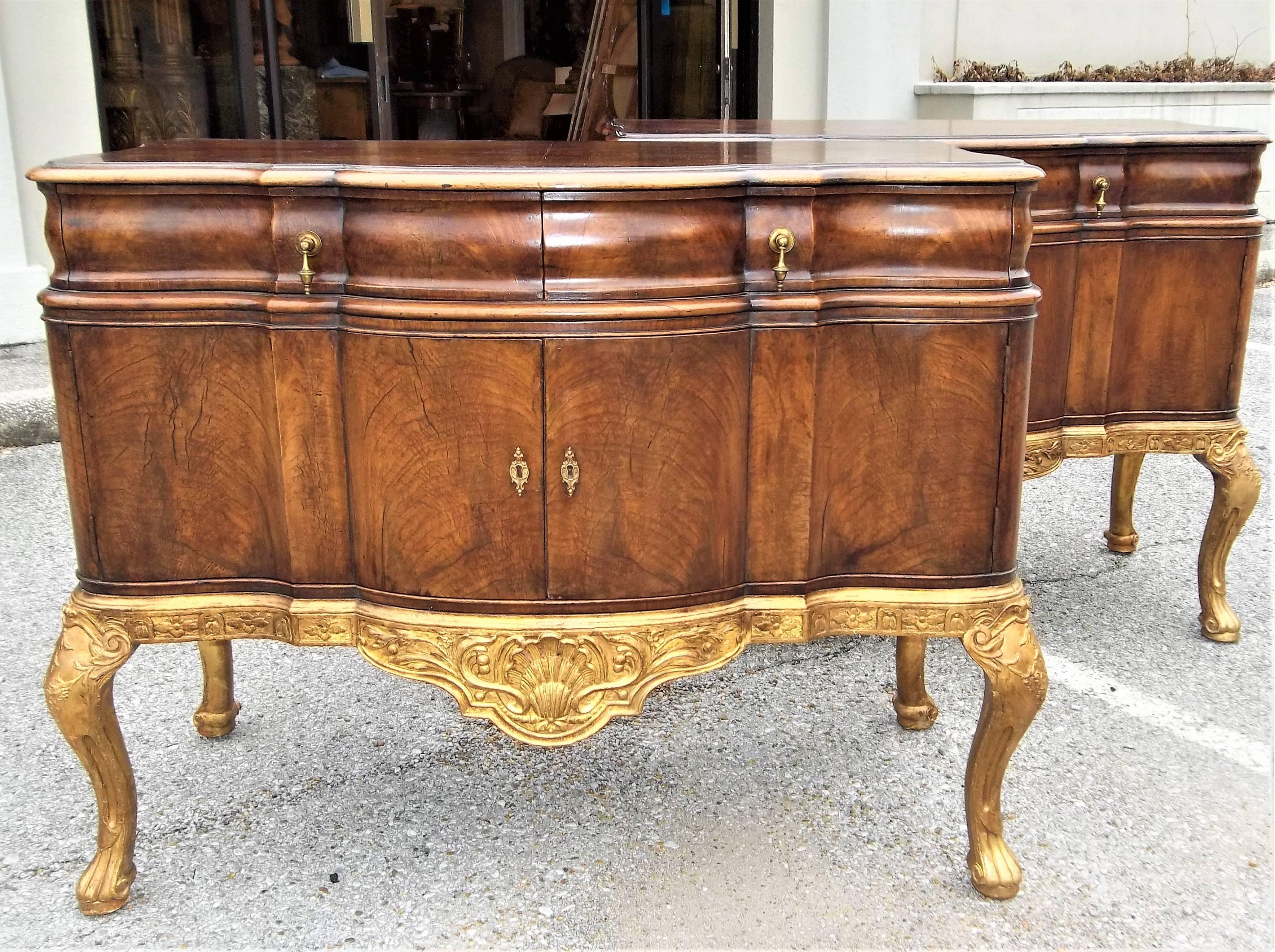 Each commode with two drawers over two doors. Figured walnut over giltwood shell frieze .Warm Cognac colored walnut. Very pretty patina. Nicely aged gilding. One key (unlocks / locks both sets of cabinet doors). Original hardware. Late