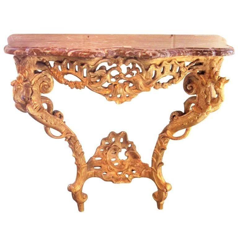 A well and profusely carved Louis XV console in the Rococo style. Each leg starting as a climbing vine but turning into dragon's tail and ending as a winged dragon. The lower stretcher and the top skirt in pierced rocaille shells. The skirt further