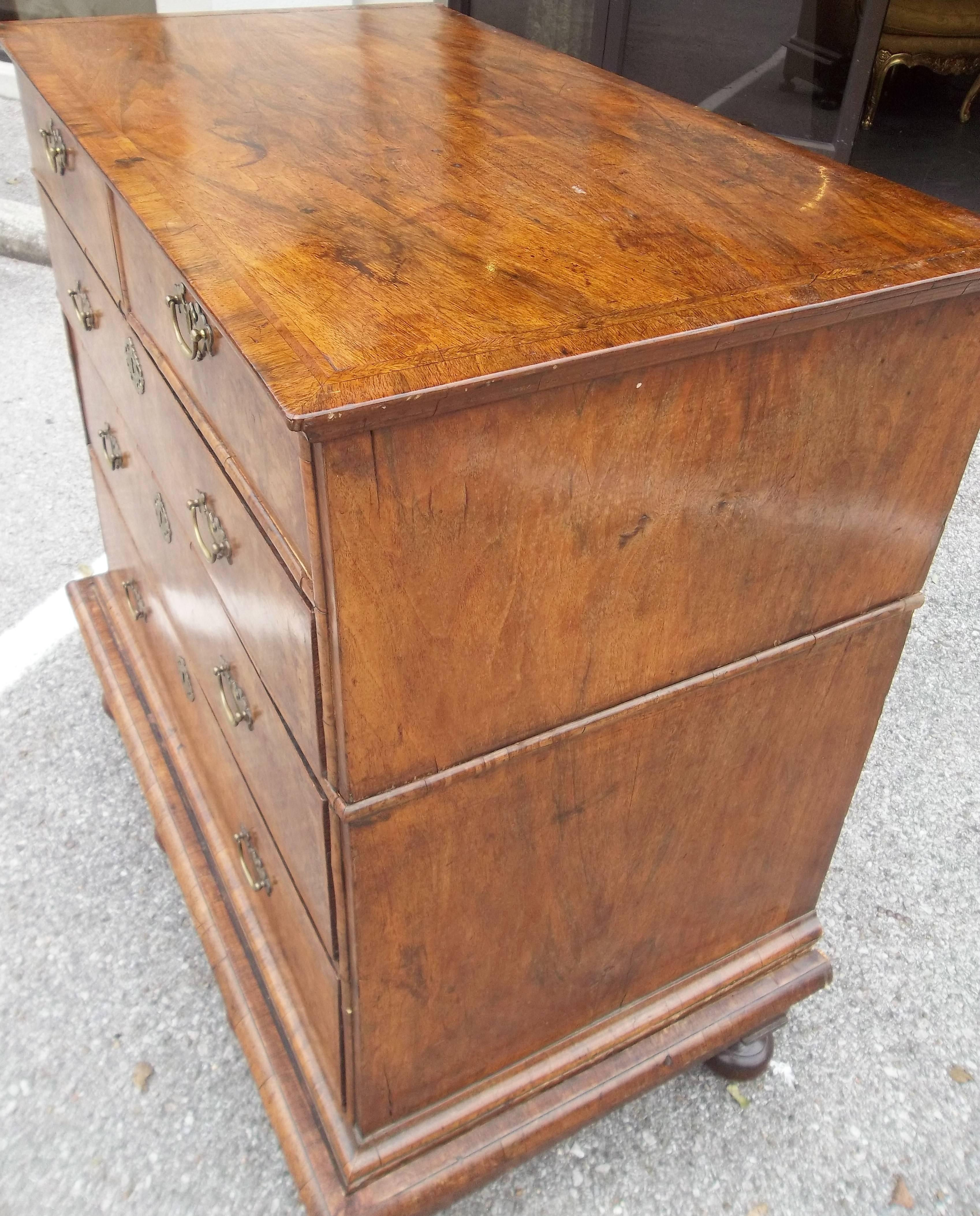 William and Mary in transition to Queen Anne, feather banded walnut chest on stand.
Late 17th century, pretty color and fine patina .
Sturdy. In three parts, the upper section with cross banded rectangular top and molded edge, above two short and