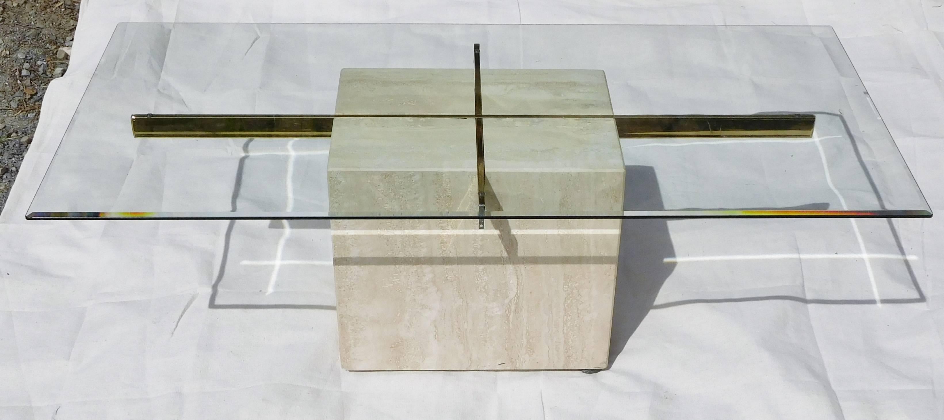 This iconic Italian-made coffee table designed by Artedi of the United Kingdom, has a beveled glass panel sitting on a polished brass cross which is embedded in a Travertine cube. Underneath, the table is marked in blue stencil: Made in