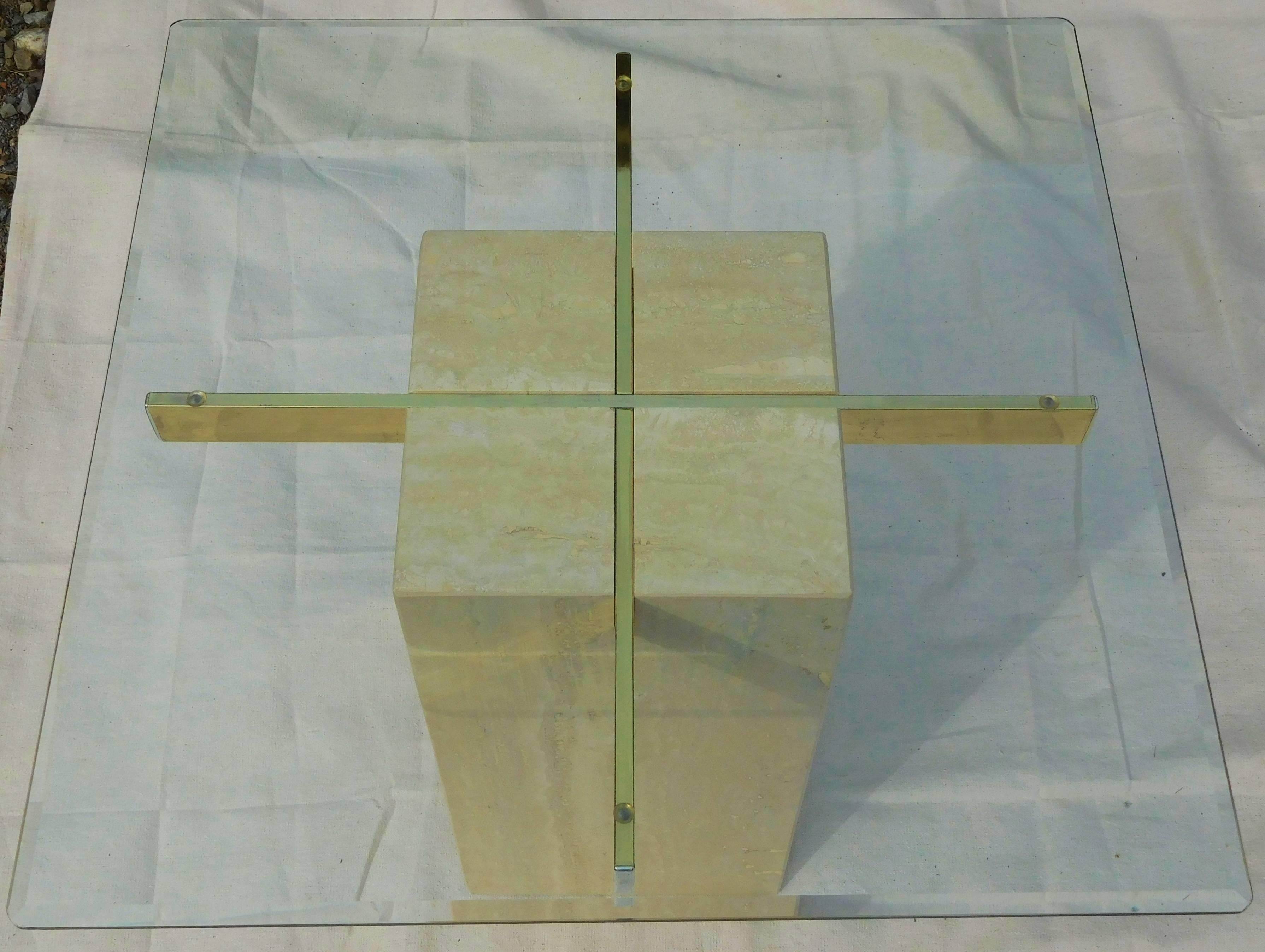 This stylish Italian-made coffee table designed by Artedi of the United Kingdom, has a beveled glass top sitting on a polished brass cross which is embedded in a Travertine cube.

The table provides an artful design element to a room, while