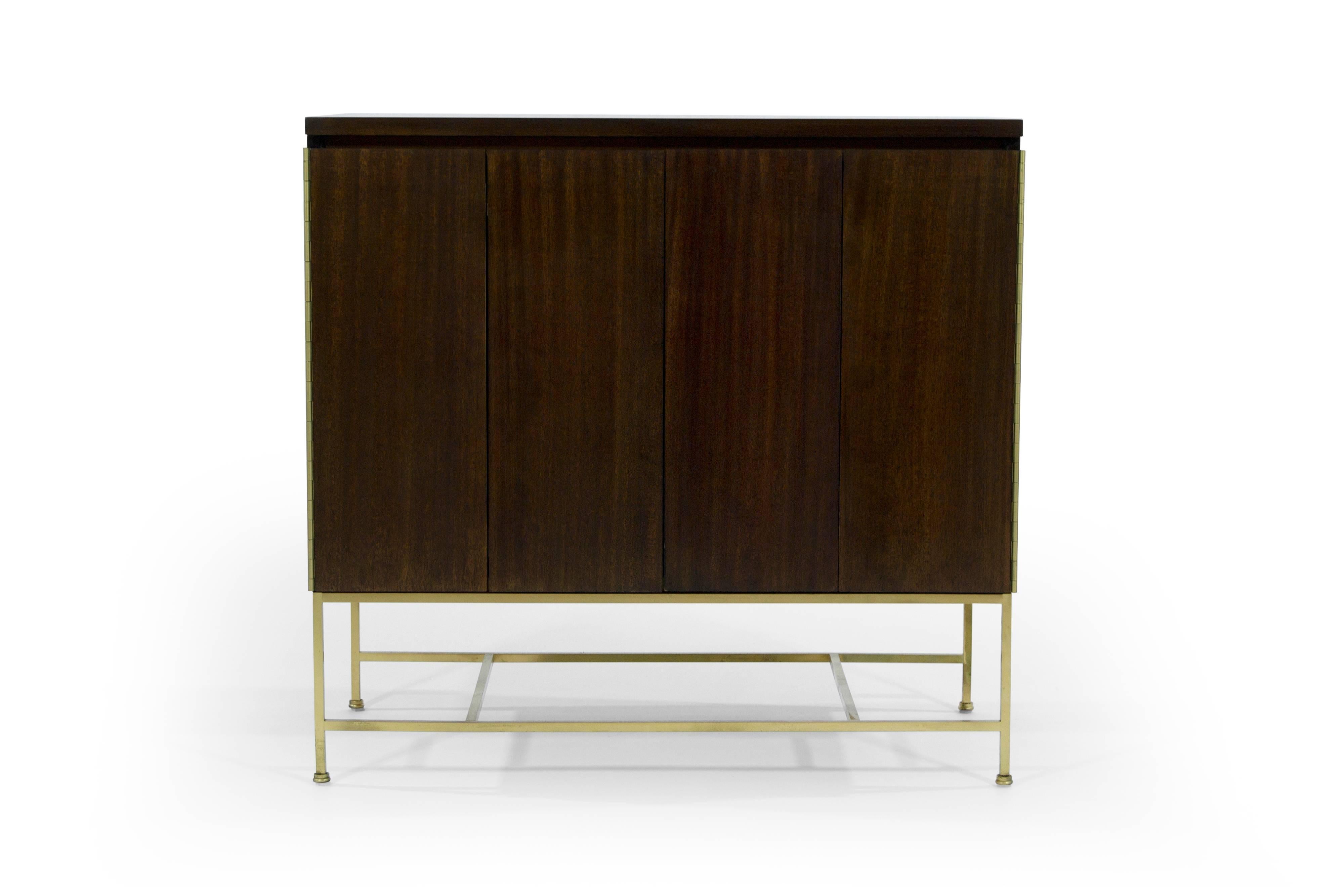 Mahogany chest of drawers designed by Paul McCobb, part of his Calvin Group collection, circa 1950s. 

This item features bi-fold doors which open up to reveal four drawers, providing ample storage space.

Mahogany case and brass base fully