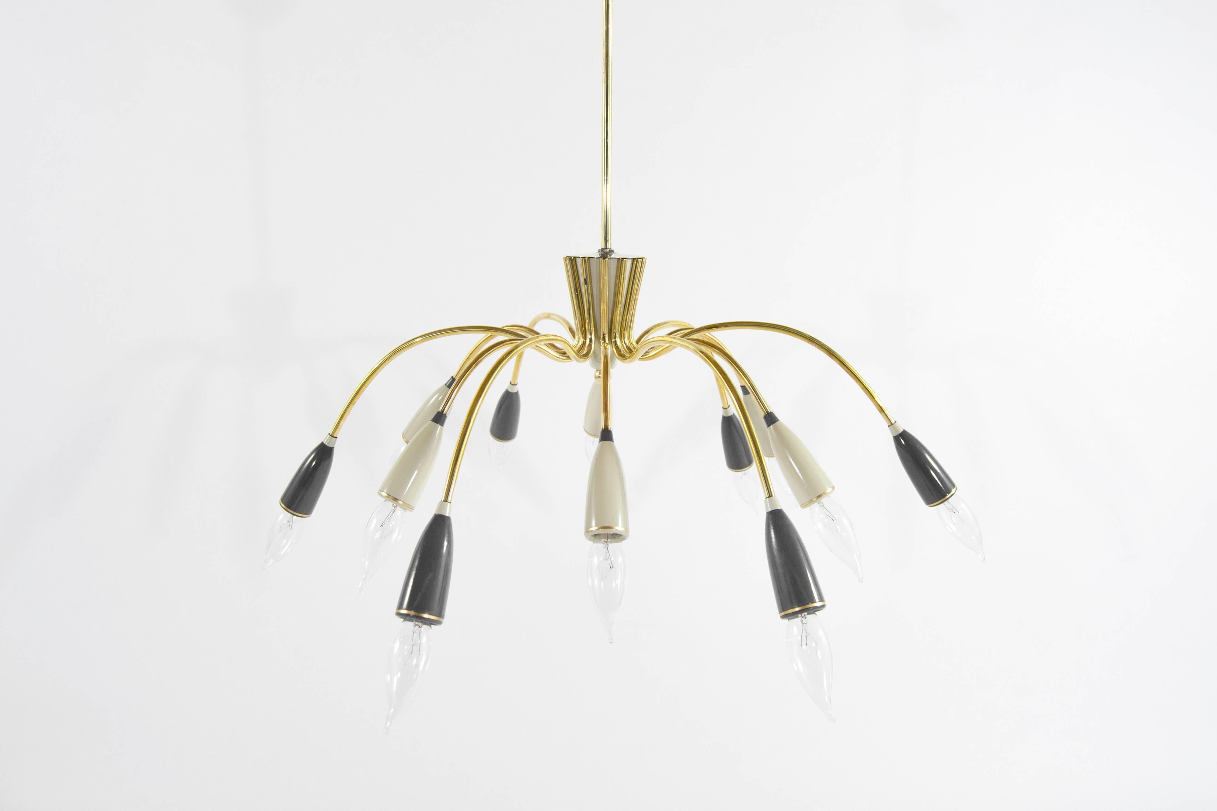 Stunning Italian brass chandelier, in the style of Stilnovo and inspired by the bold designs of the 1950s. This exquisite piece features 10 elegant arms, each adorned with enameled sockets that add a touch of sophistication and refinement to any