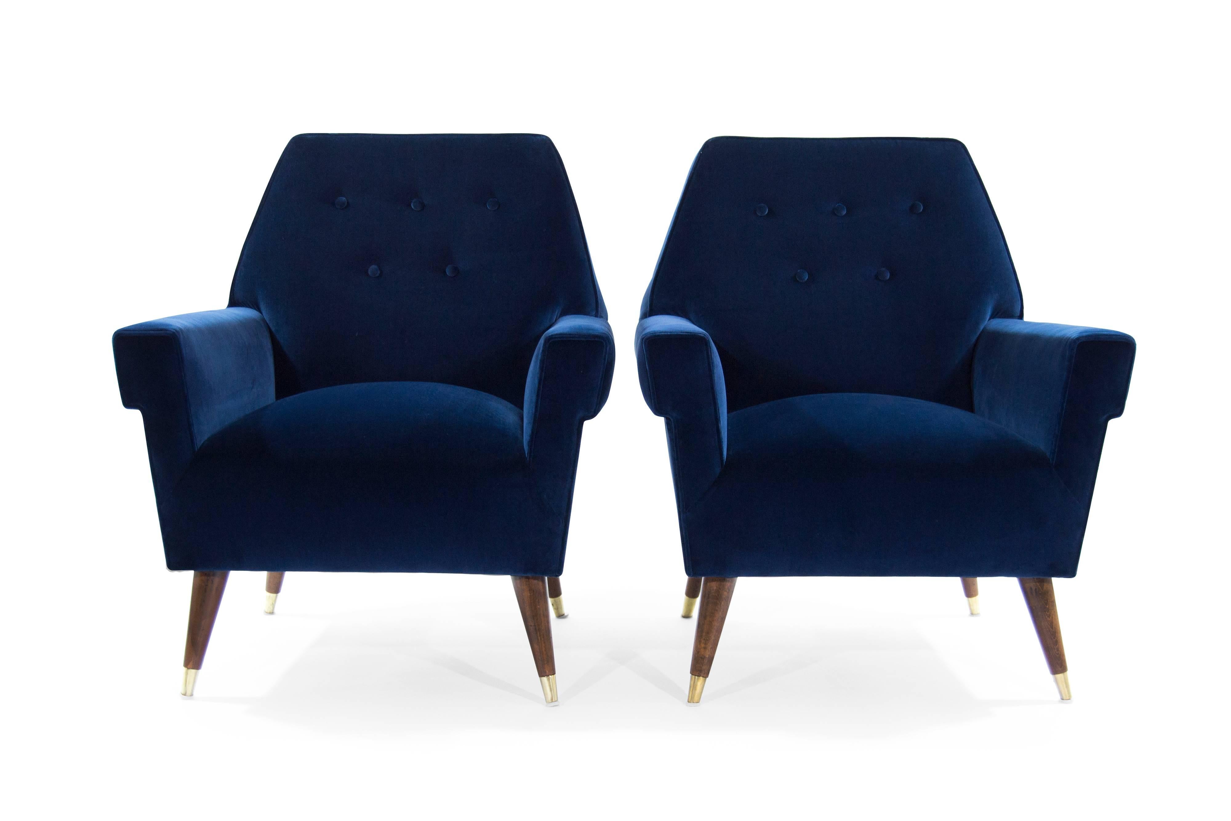 Stunning pair of lounge chairs featuring splayed walnut legs ending in brass sabots. Larger scale and extremely comfortable. Original from Italy, circa 1950s. In the style of Gio Ponti.

Newly upholstered in a beautiful navy blue velvet. Legs fully