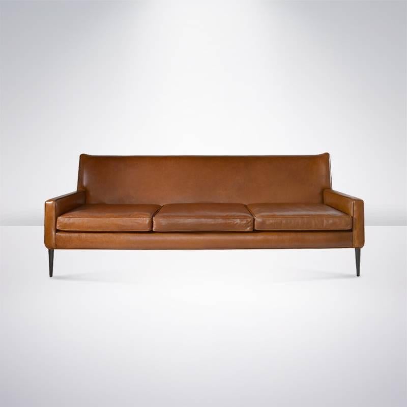 Designed by Paul McCobb for Directional, newly recovered in cognac leather. Walnut legs newly refinished.