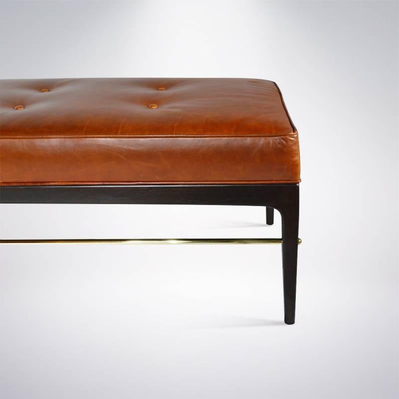 A Mid-Century bench newly fitted with custom brass rods, adding a touch of elegance and grace. Solid walnut frame has been newly refinished in dark walnut. Re-upholstered in cognac leather.