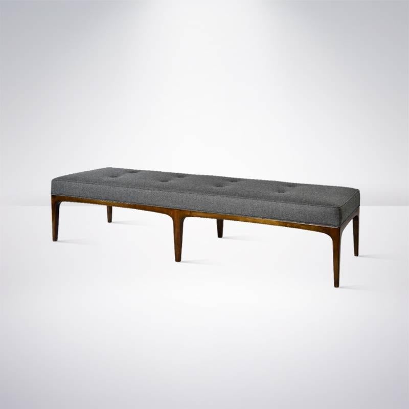 An exquisite clean lined, extra long bench is the style of Paul McCobb. Walnut frame newly refinished in a medium tone. Top newly upholstered in grey wool.