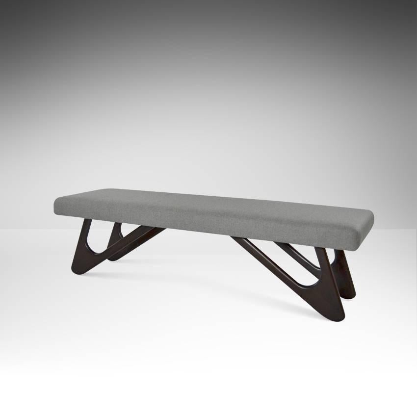 Sculptural bench newly recovered in grey wool. Boomerang shaped legs have been refinished in a rich dark chocolate tone with a satin finish.