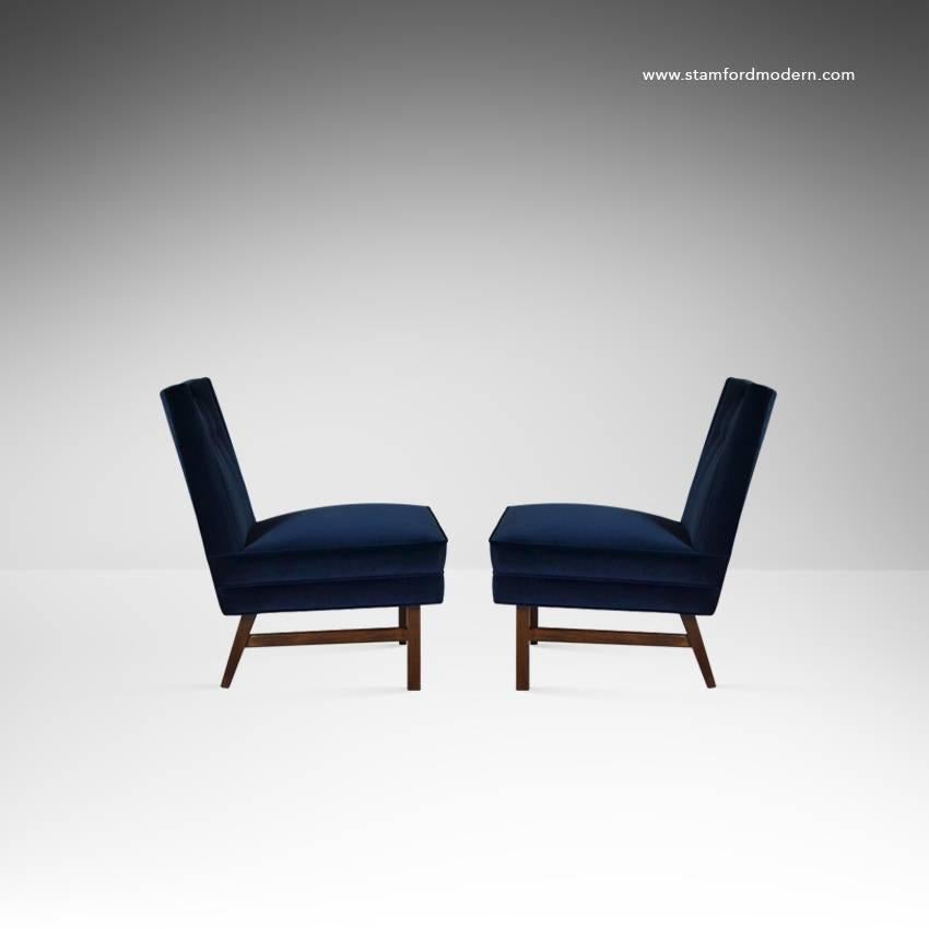 Rare pair of lounge chairs designed by Harvey Probber for Probber Inc. Newly upholstered in navy blue velvet, walnut base newly refinished in natural. This pair features a very cool solid brass handle atop the chair of easy movement.