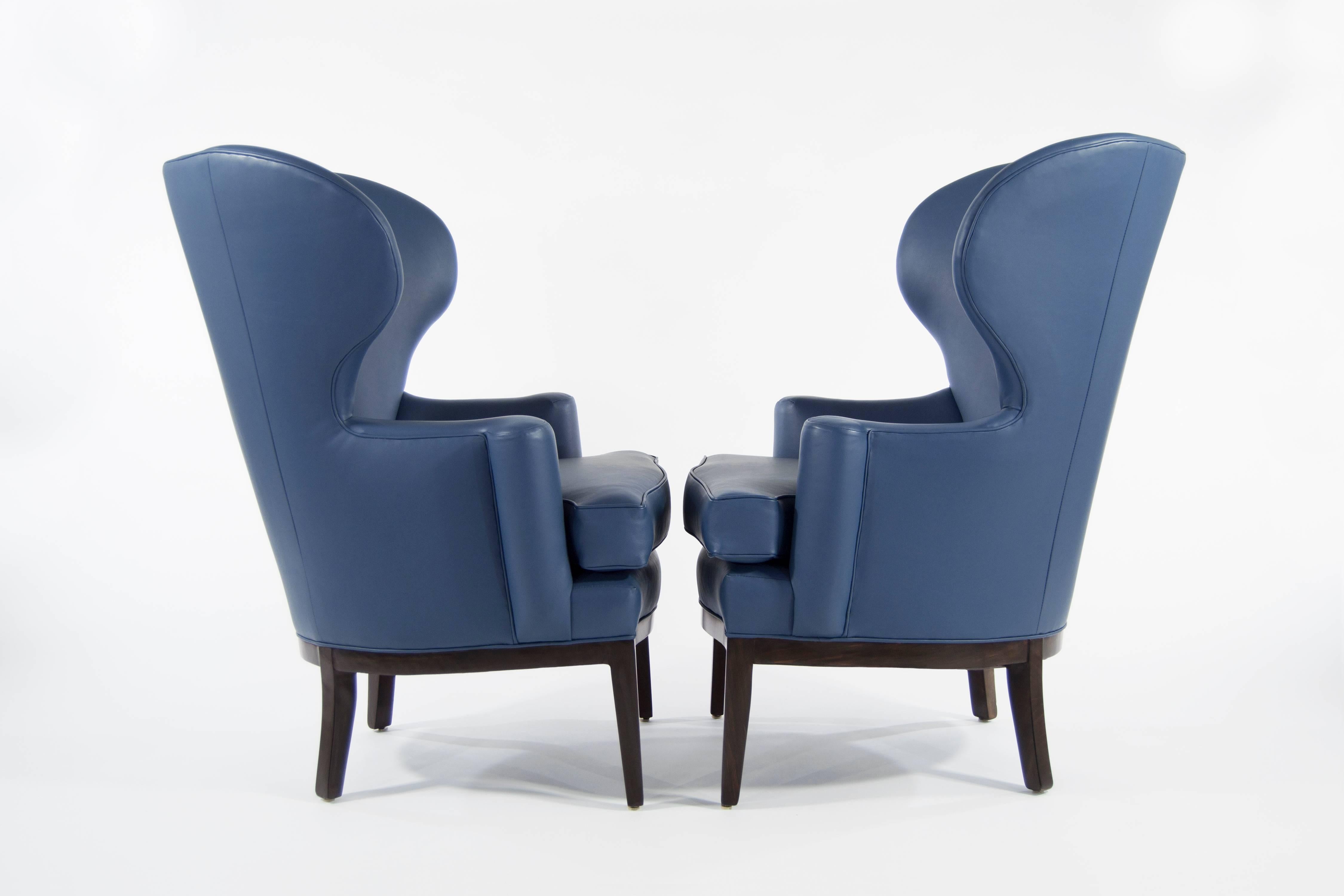 Extremely rare pair of early wingback chairs designed by Edward Wormley for Dunbar, circa 1940s. Newly upholstered in blue Spinneybeck leather, walnut bases fully restored. Priced and available individually.
