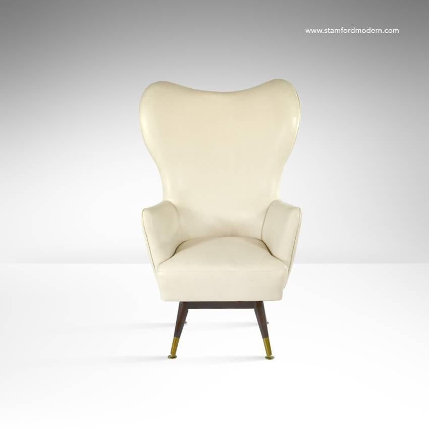 A beautifully designed swiveling wingback chair in cream leather by the Karpen Company of California, circa 1950s.