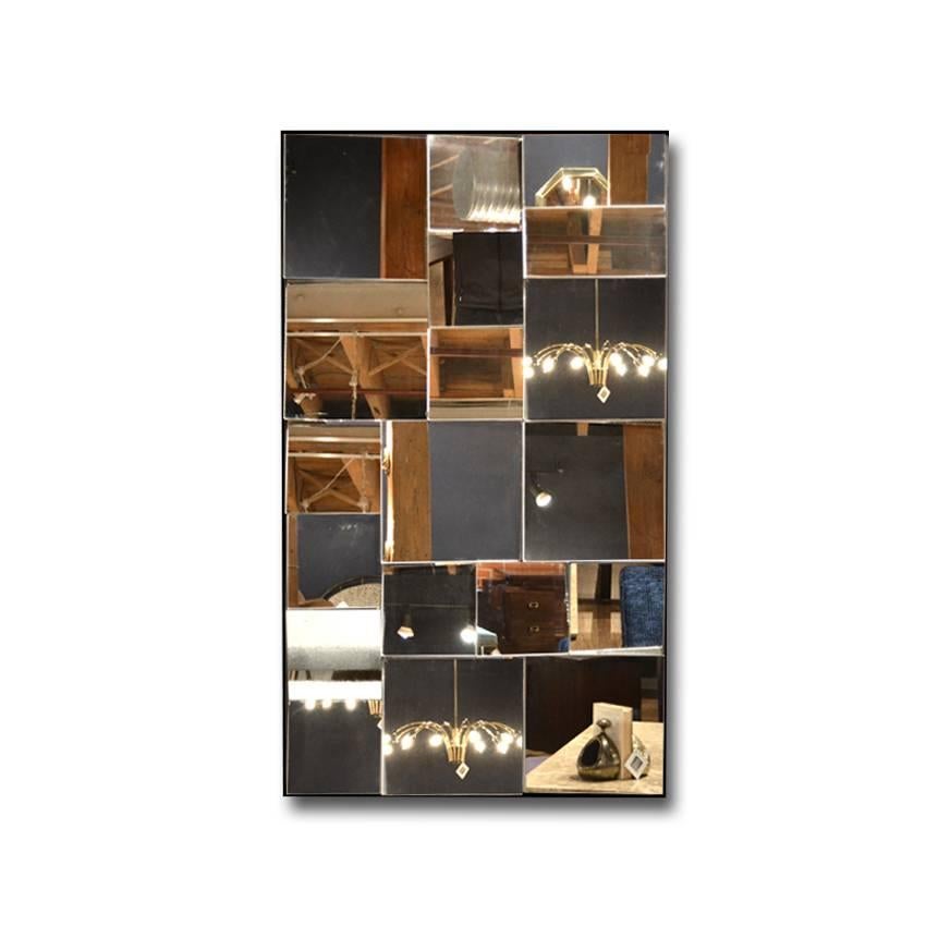 A Mid-Century Modernist segmented mirror by Neal Small. Square and rectangular panels arranged in a symmetrical manner, positioned at an angle to give off a multi-dimensional and faceted effect. A stunning piece above a sideboard, dresser or console.