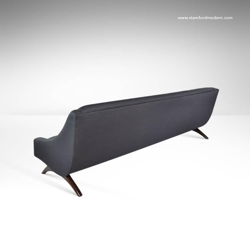 Modernist floating sofa in the style of the late Vladimir Kagan. Sculptural form ash legs newly refinished in dark walnut. Re-upholstered in dark grey twill.