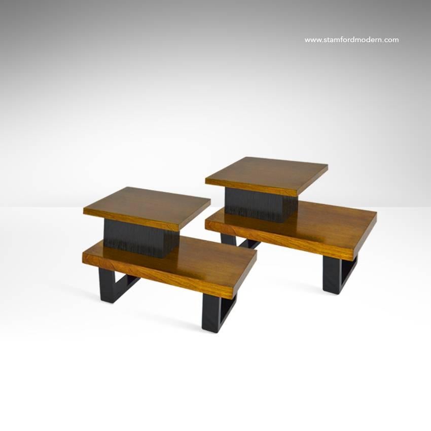 A pair of tiered two-tone side tables designed by Paul Frankl. Legs and combed oak center structured have been refinished in ebony, emphasizing the beautiful natural walnut tops.