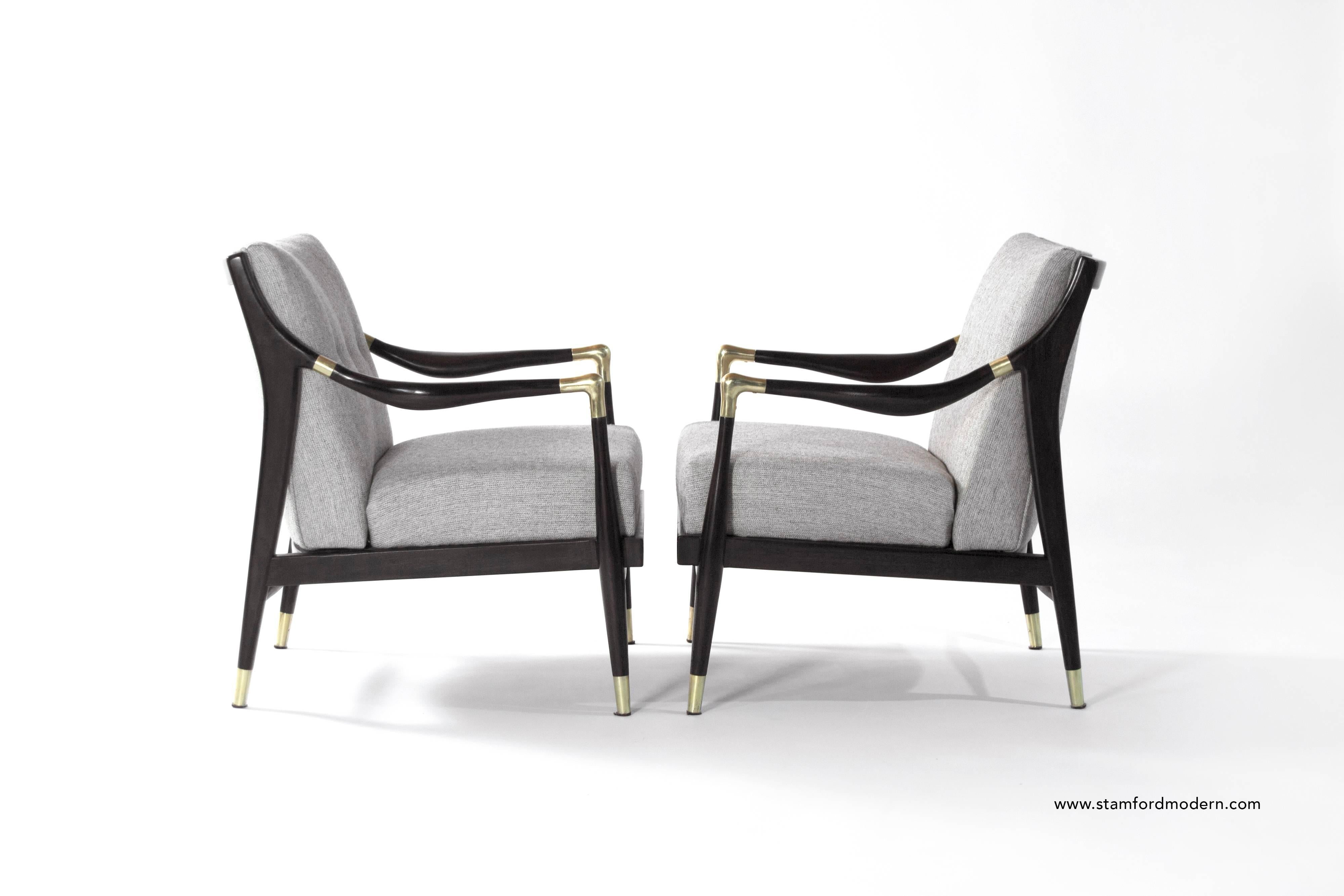 A gorgeous pair of sculptural lounge chairs with brass accents on arms and sabots in the style of Gio Ponti.