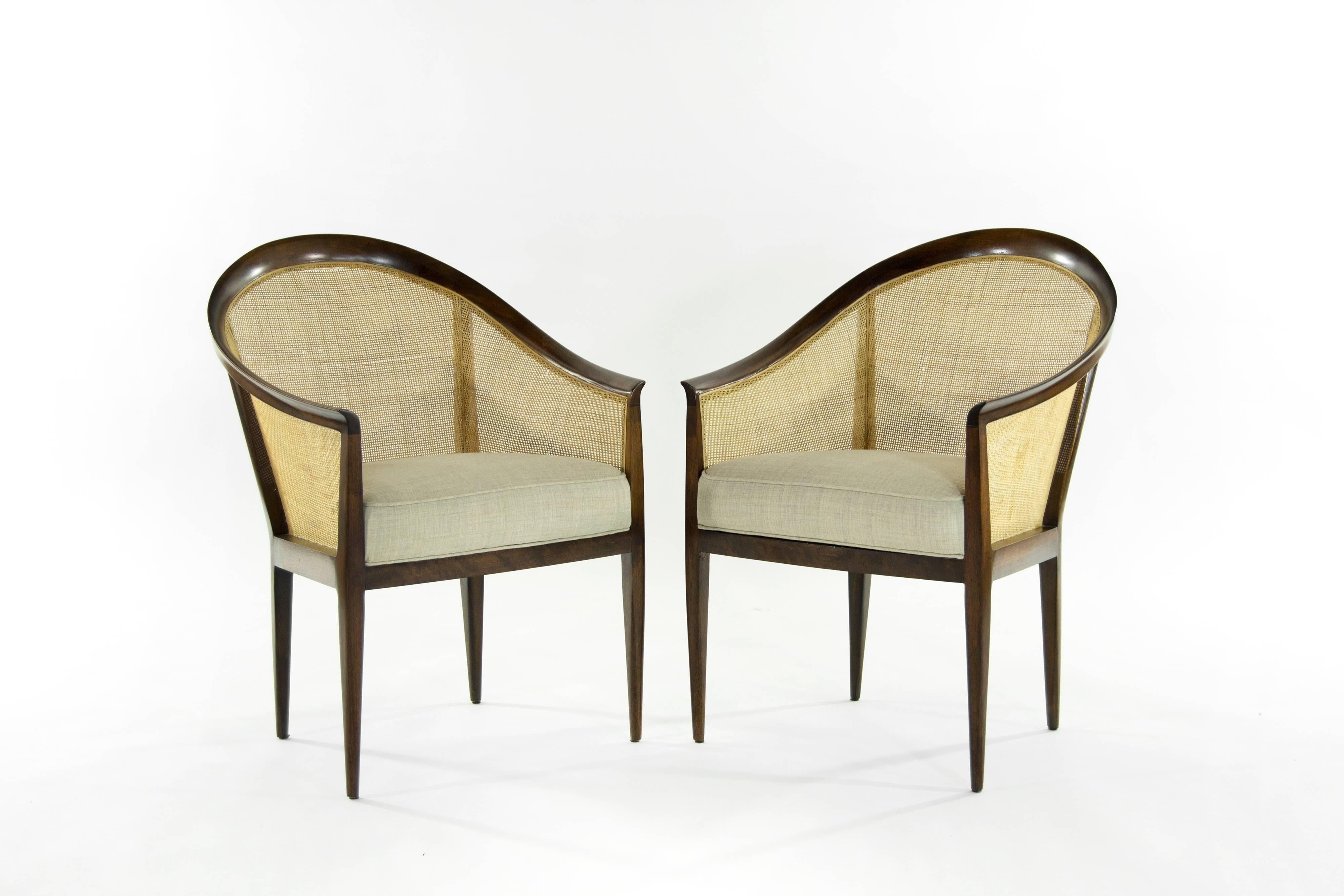 A very handsome pair of lounge chairs designed by Kipp Stewart for Directional, circa 1950s. Walnut frames newly refinished in natural, original caning in excellent condition. Seats newly upholstered in beige linen.