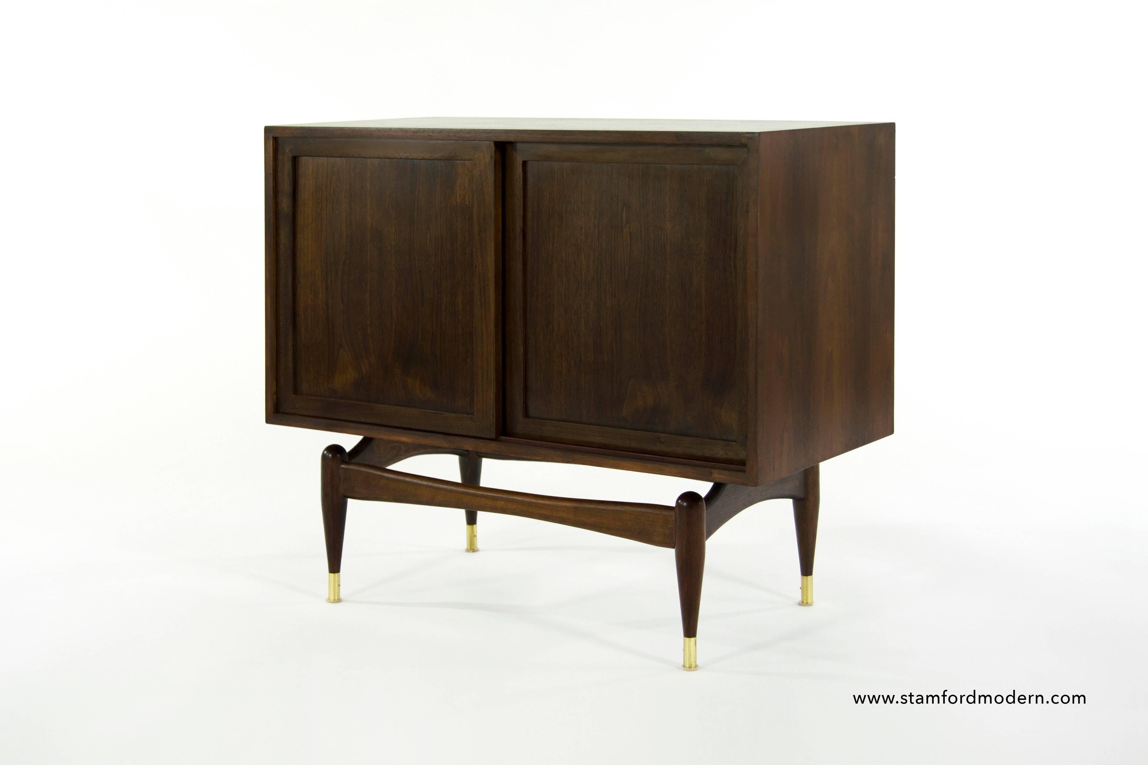Fully restored walnut cabinet or console table, this very unusual piece features dual sliding doors which open up to reveal a single shelf as well as a sculptural form base with brass sabots.