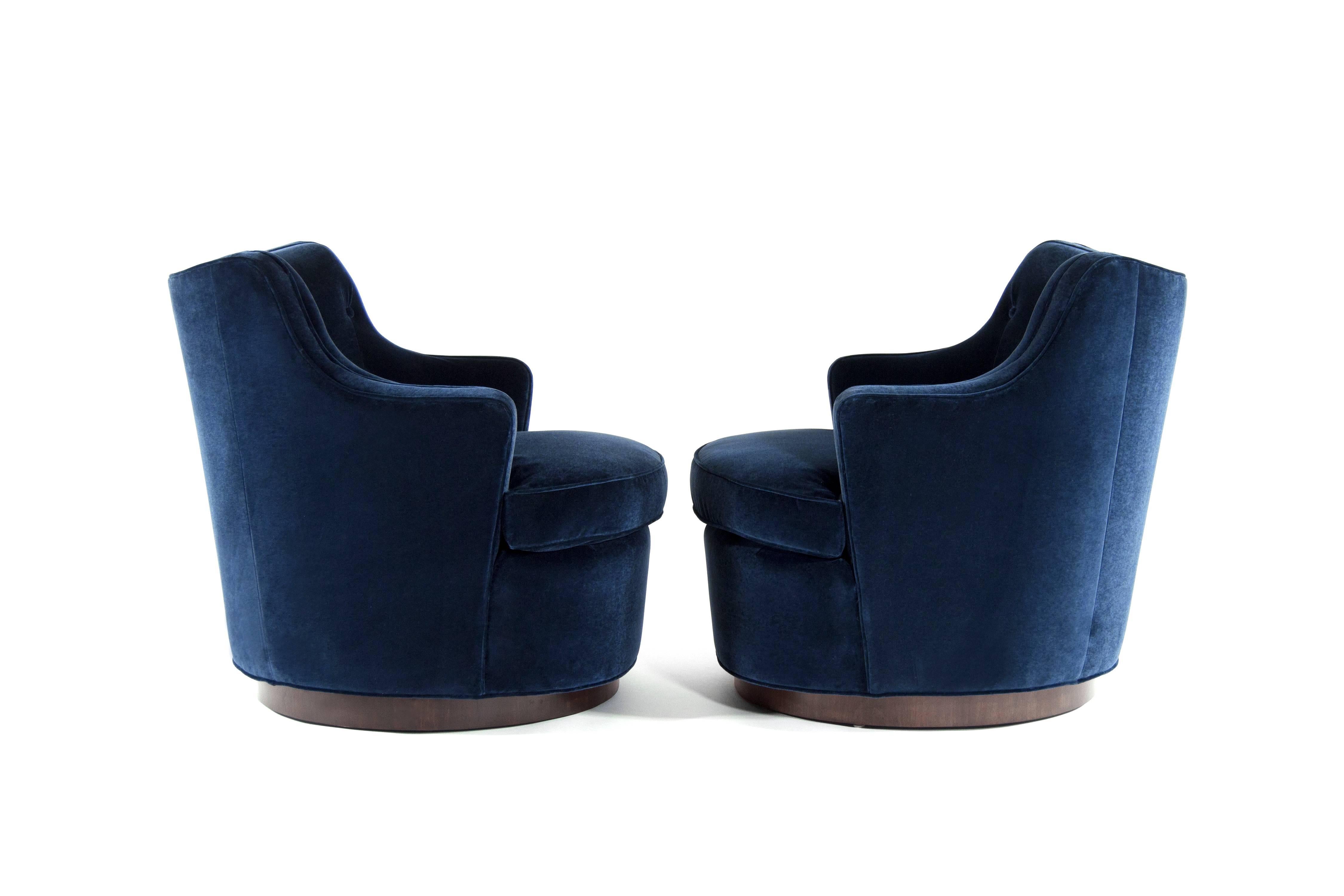Pair of swivel chairs designed by Edward Wormley for Dunbar model 4626, circa 1950s.

Newly upholstered in navy blue velvet, walnut base fully restored.