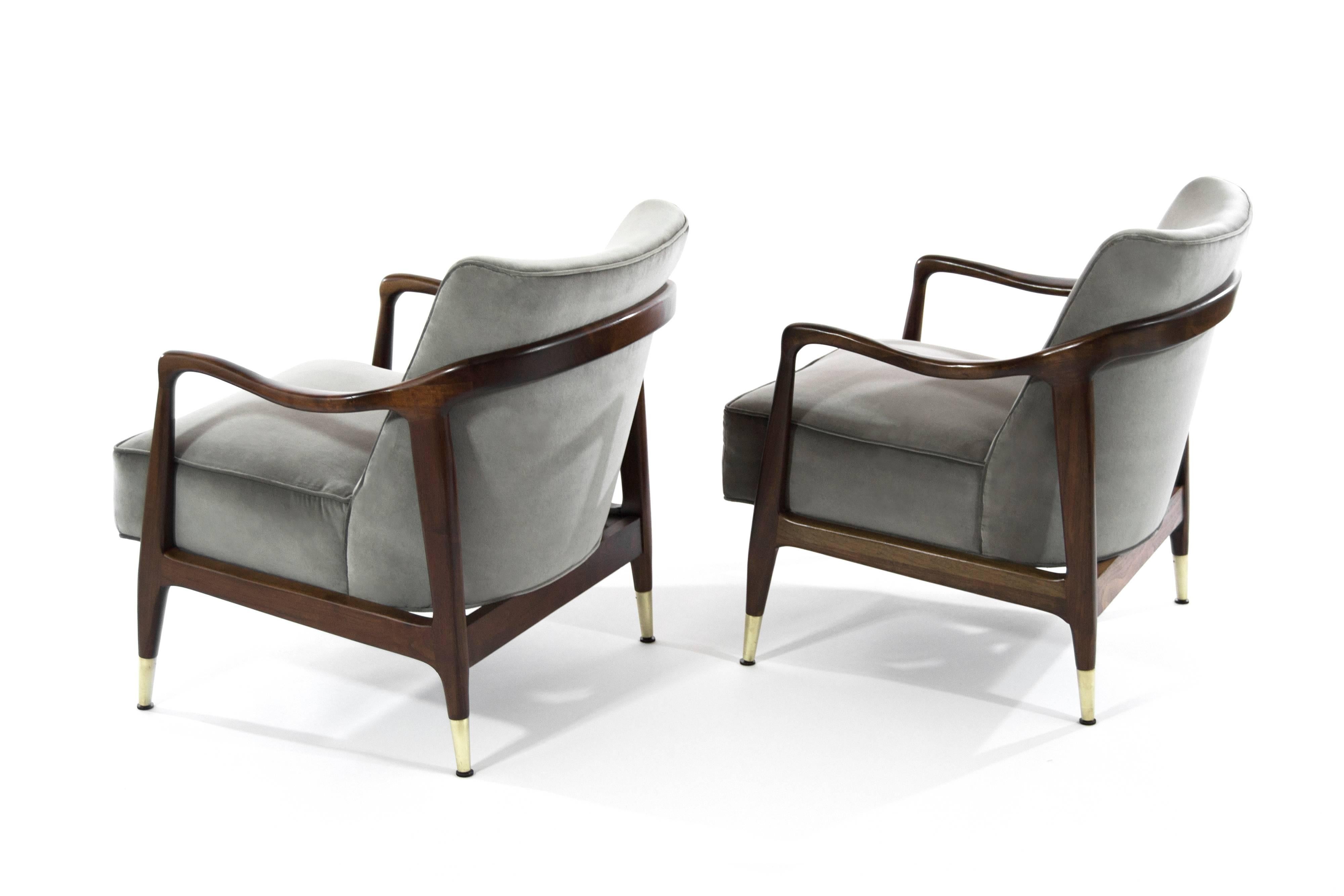 Rare pair of Italian lounge chairs featuring sculpted walnut frames and brass sabots. Walnut frames fully restored, newly upholstered in charcoal velvet.