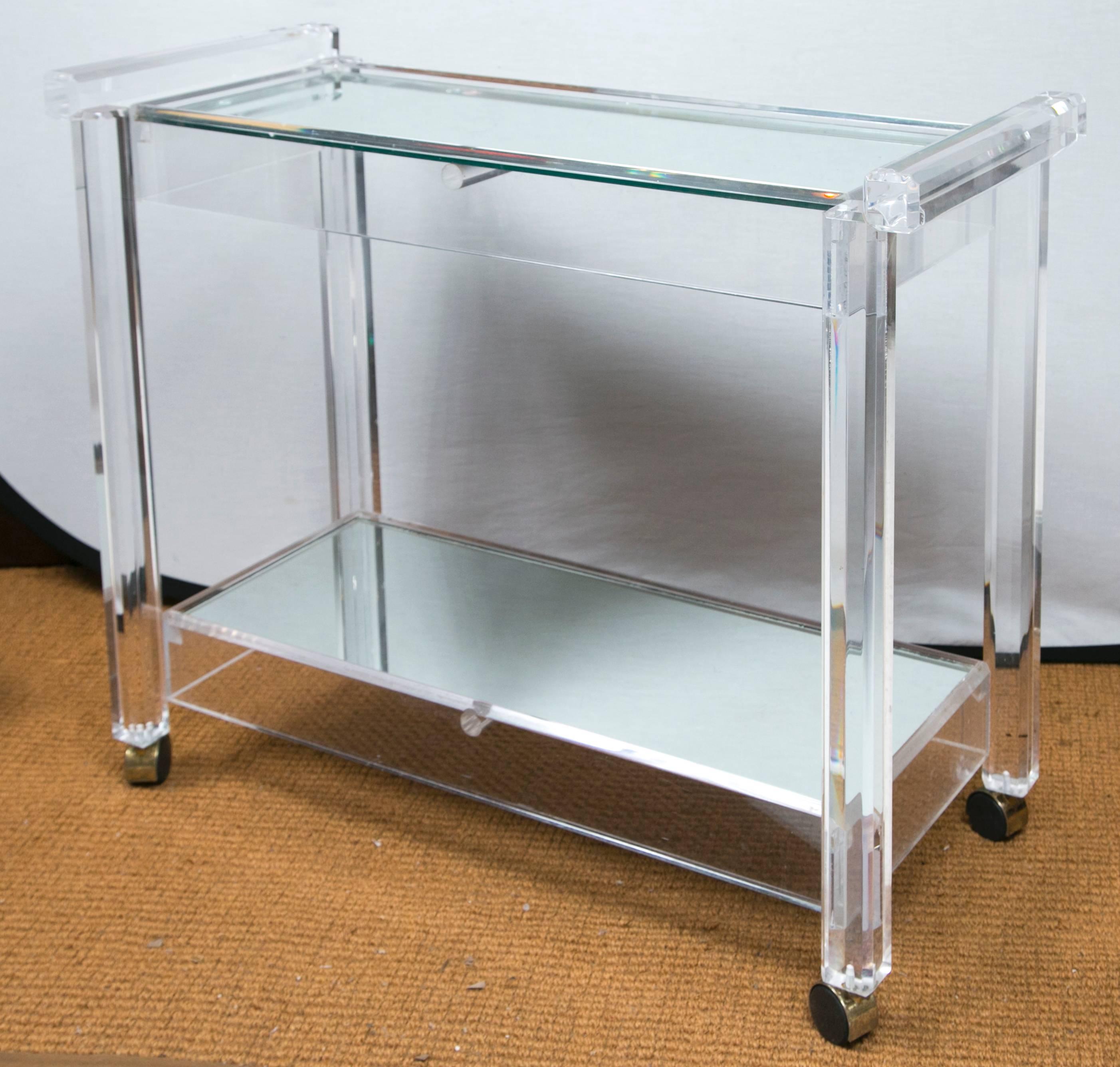 A boldly subtle vintage Lucite bar cart in incredible condition. It has incredible weight and presence but remains transparent due to the use of material. Each tier has inset antiqued mirror that expands the piece visually. It's a wonderful piece