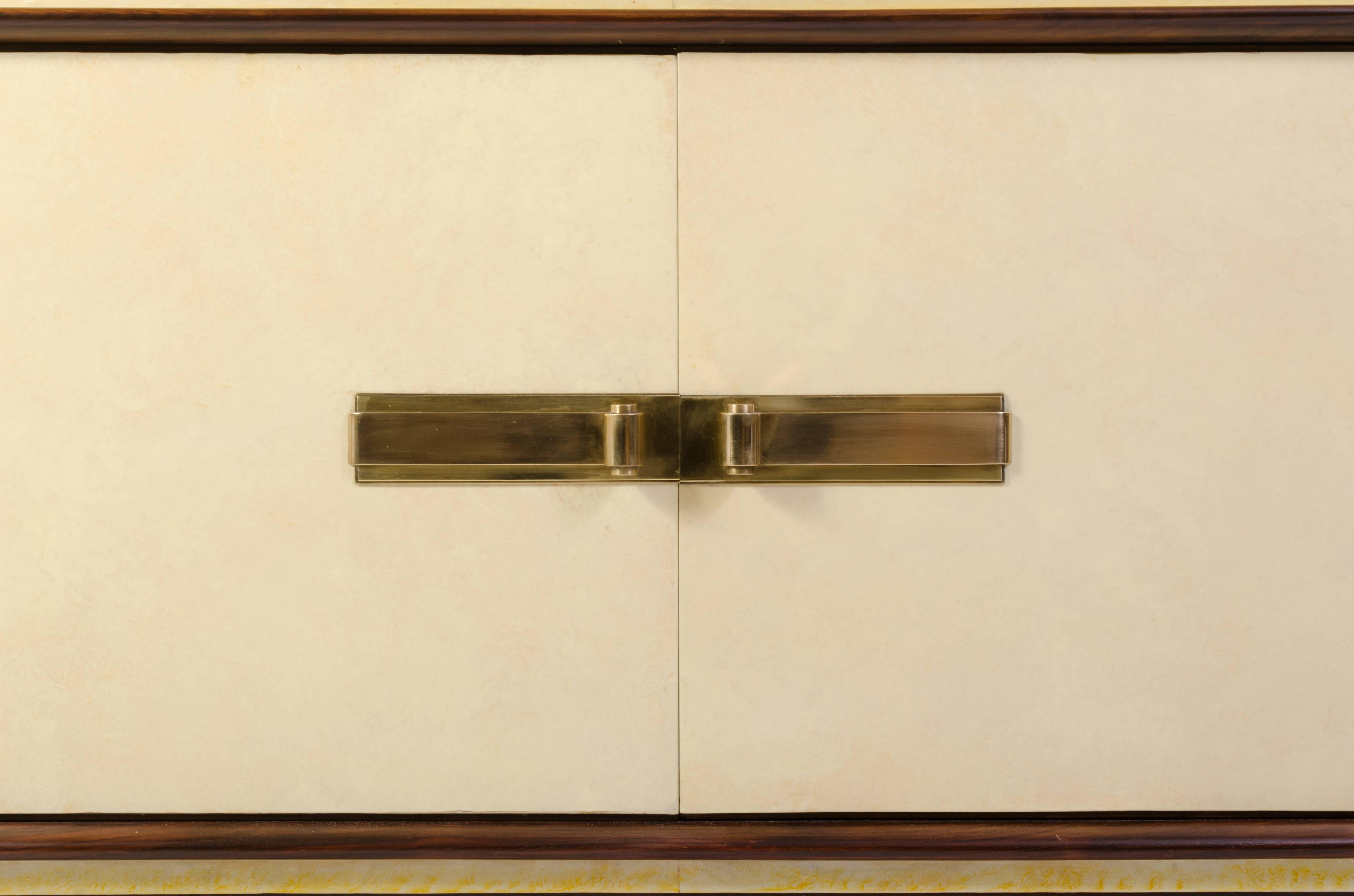 Nothing is as stately and elegant as this piece. An amazing sideboard from the 1930s attributed to the great Paul Dupré-Lafon. Wrapped in vellum, trimmed and pedestaled with rosewood, and adorned with brass. Two generously sized doors open to
