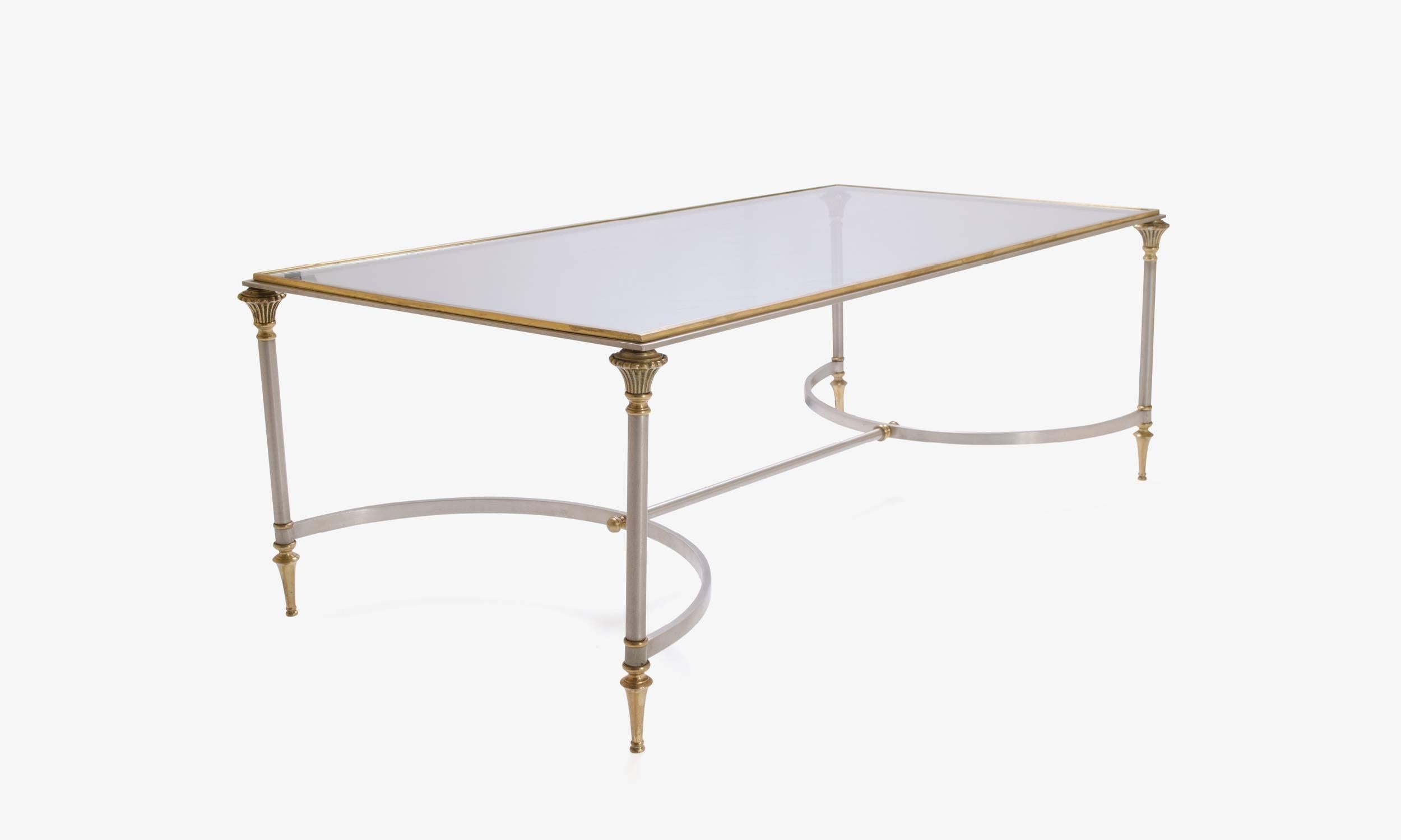 An elegant design with superior construction. Brass and steel contrast playfully with one another throughout this wonderful cocktail table in the manner of Maison Jansen. From finials to fleurs every accent of this table does not go unnoticed. The