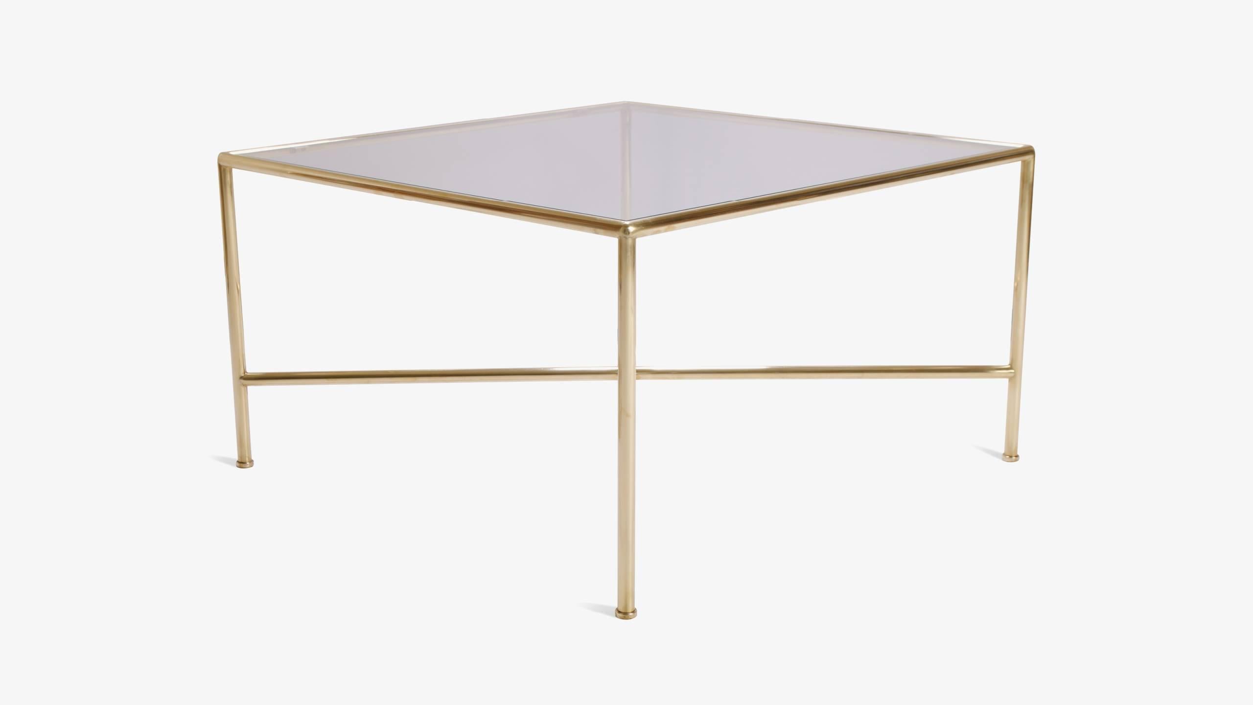 A Classic well designed cocktail table perfect for any room. Crafted from tubular brass, the table frame extends downward featuring a cross-stretcher. Each leg is finished with an extruded ornament. Well proportioned and would work in a number of