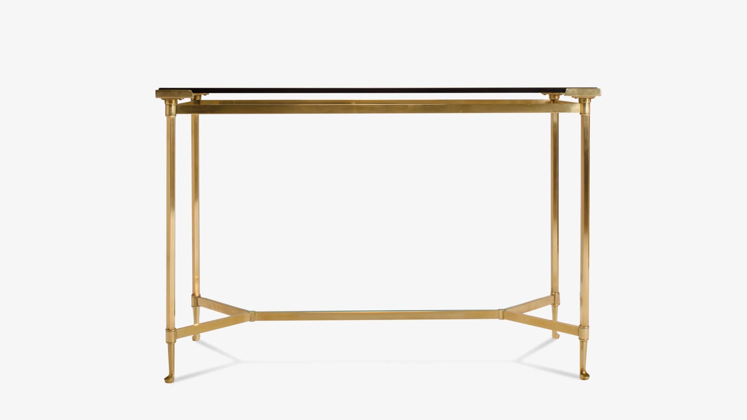 An impeccable piece of French design. This petite console elegantly utilizes superior materiality throughout its form. Solid brass accents; four feet and four corner supports, frame the entirety of the console. A minimal brass cross stretcher is an